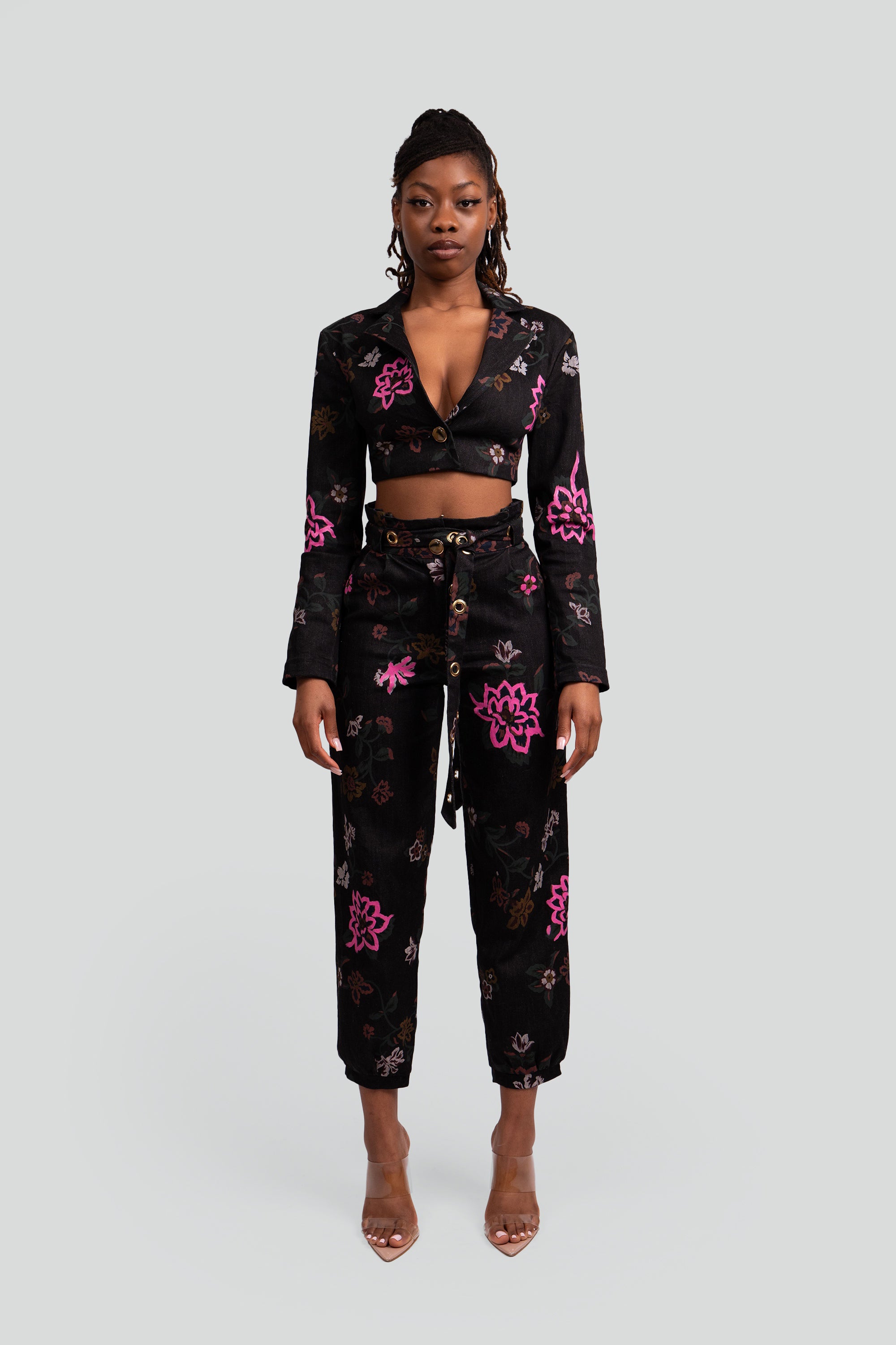 Woman wearing a black floral cropped suit set on a plain background
