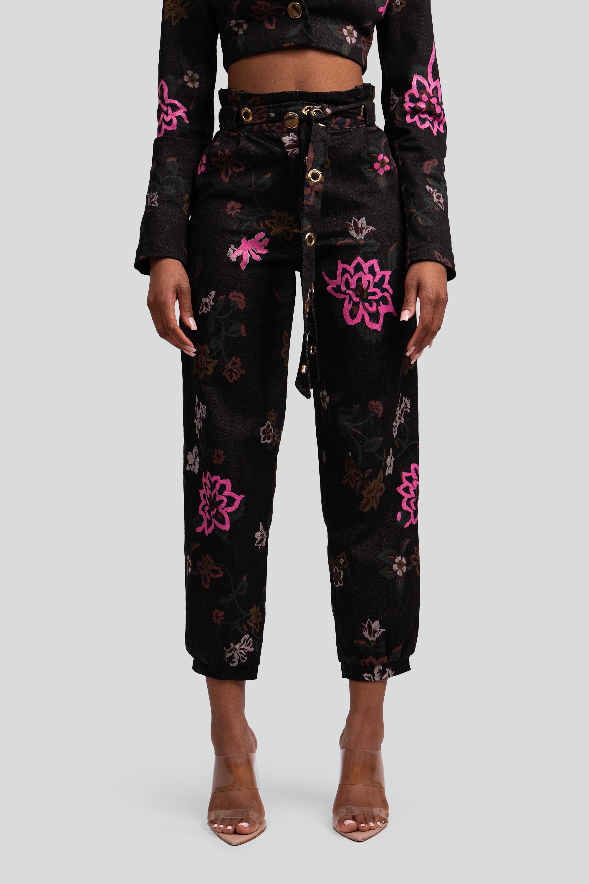 Close up view of a black floral pant worn by a woman on a plain background