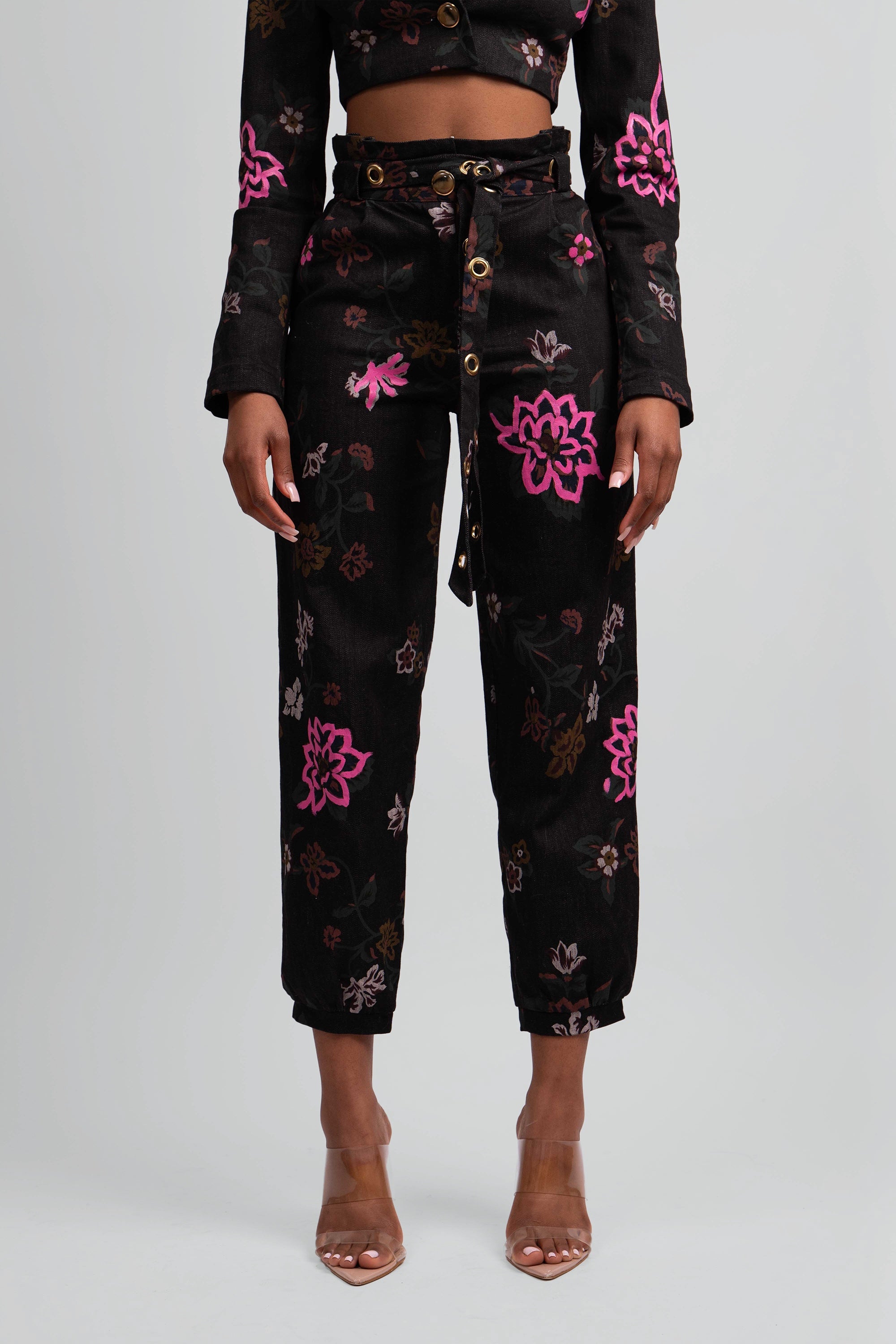 Close up view of a black floral pant worn by a woman on a plain background