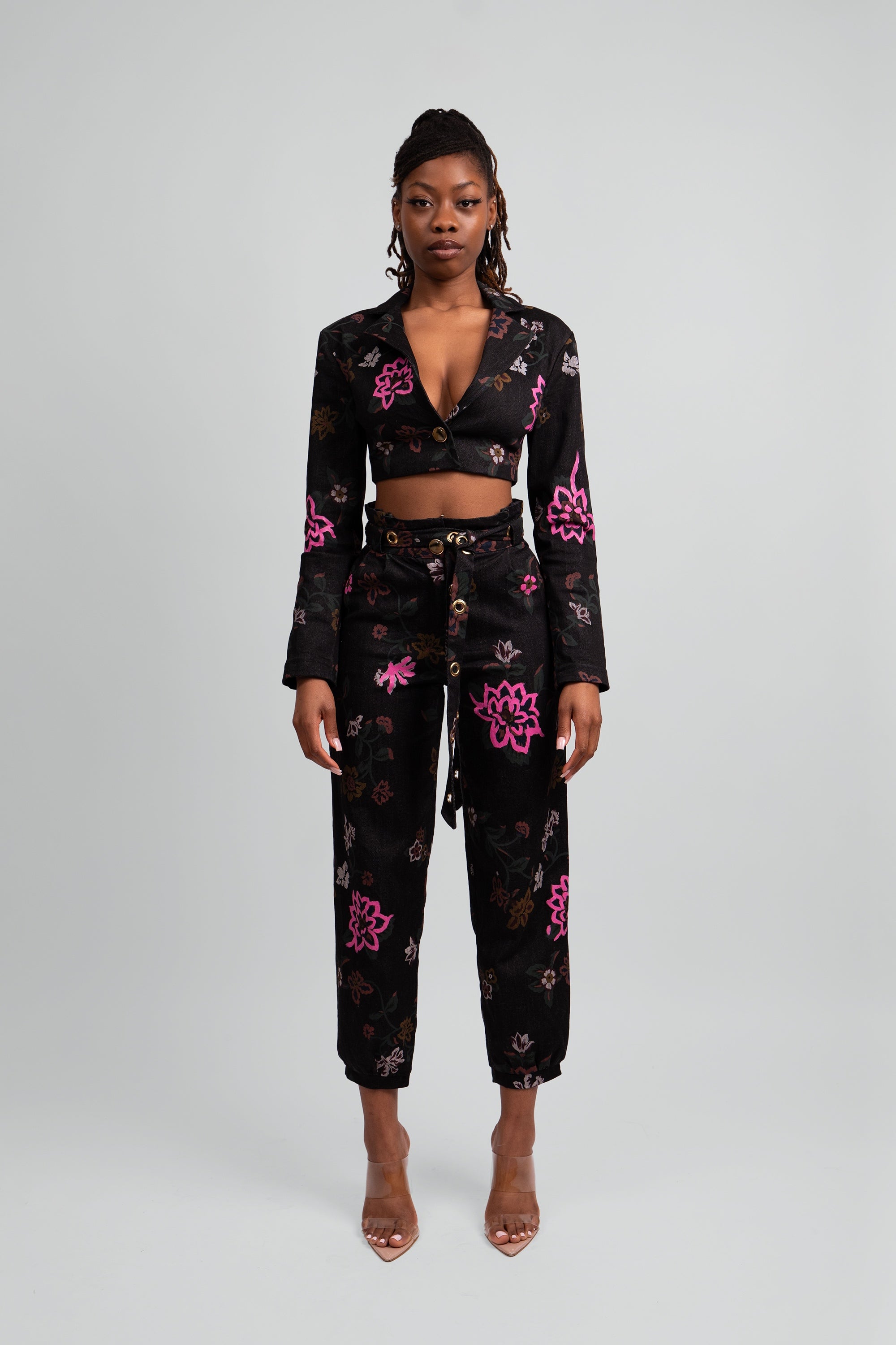 Woman wearing a black floral cropped suit set on a plain background