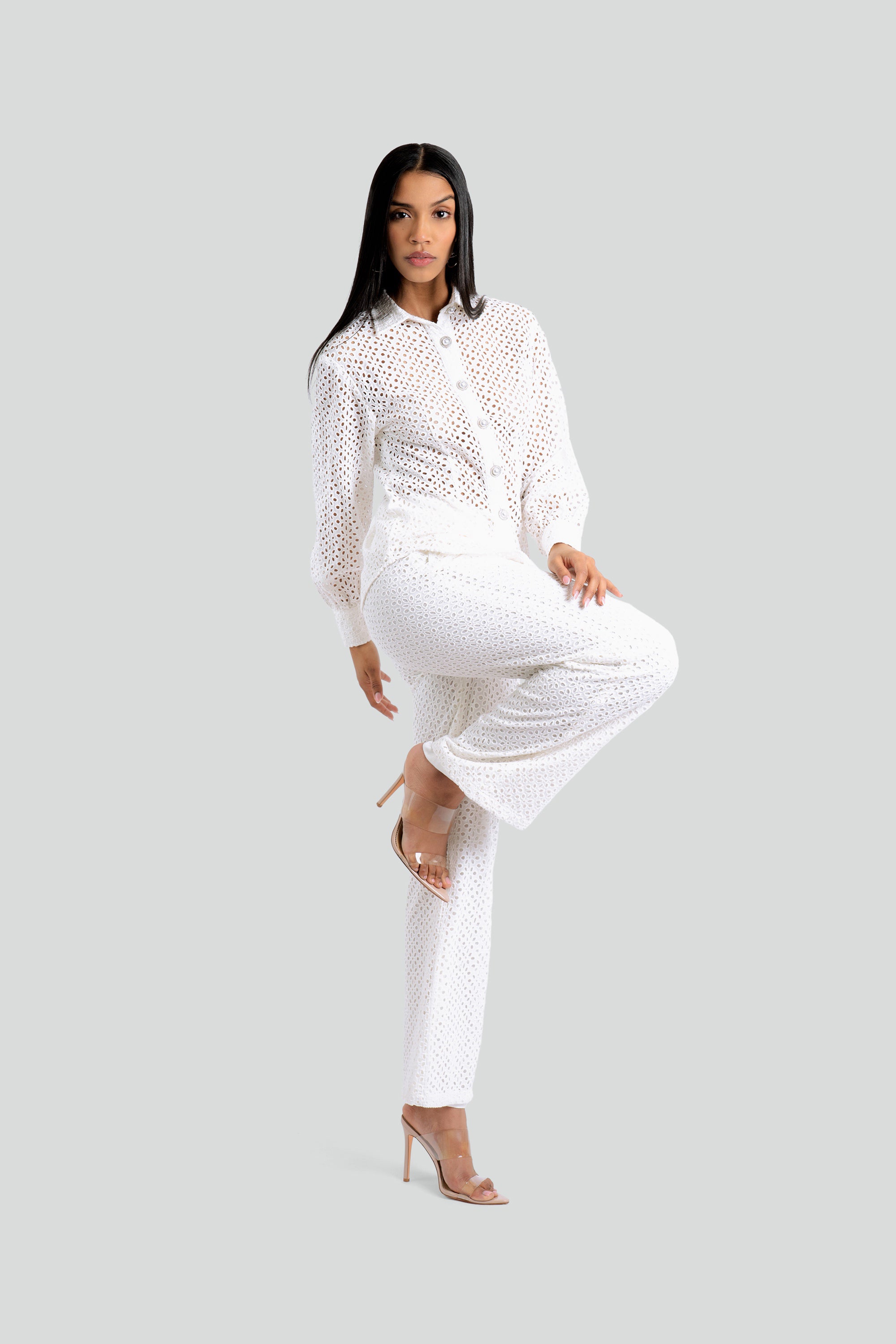 Woman wearing a white eyelet lace outfit on a white background