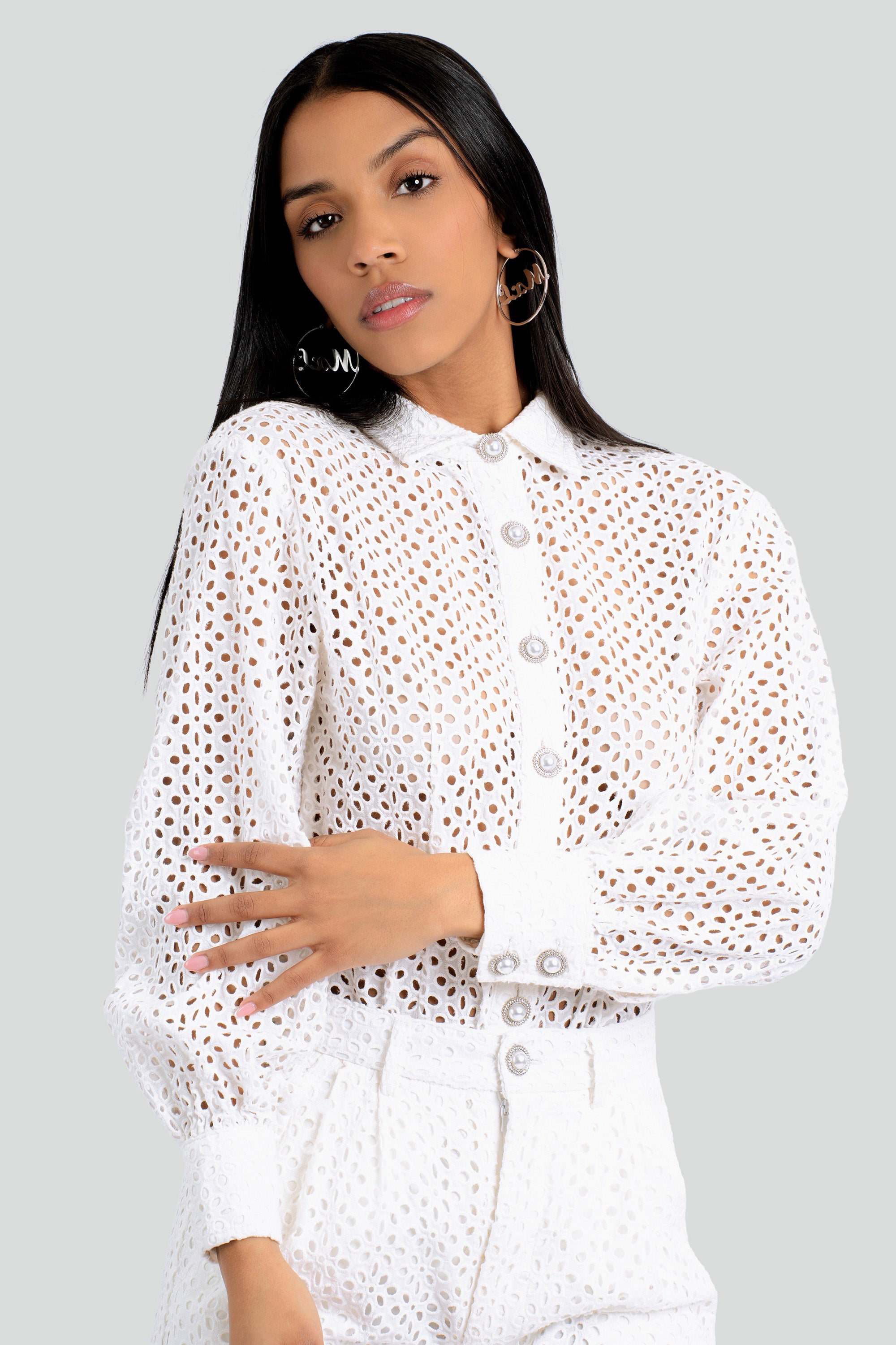 Woman wearing a white eyelet lace outfit on a white background