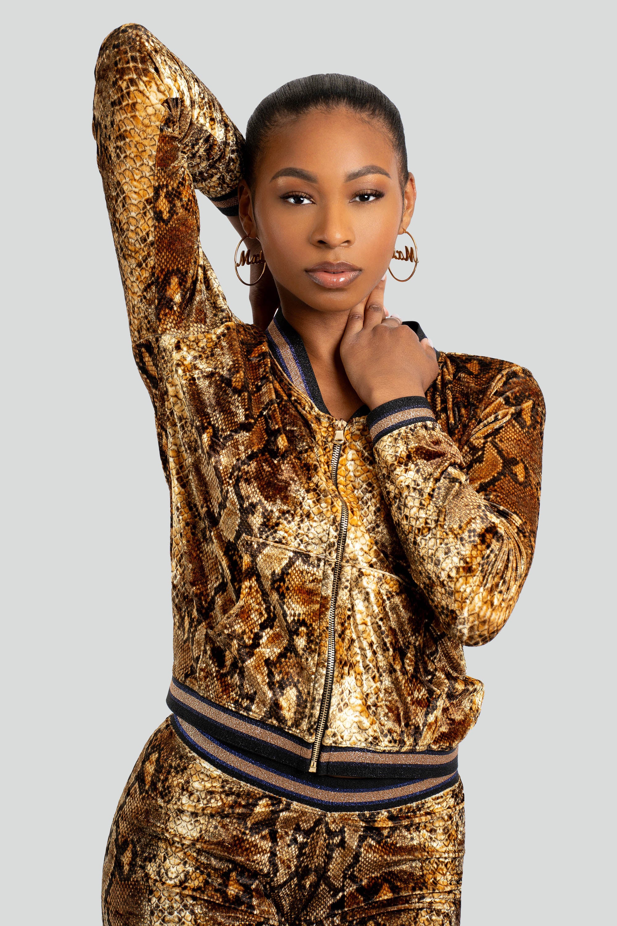 Woman wearing a gold snake print tracksuit on a white background