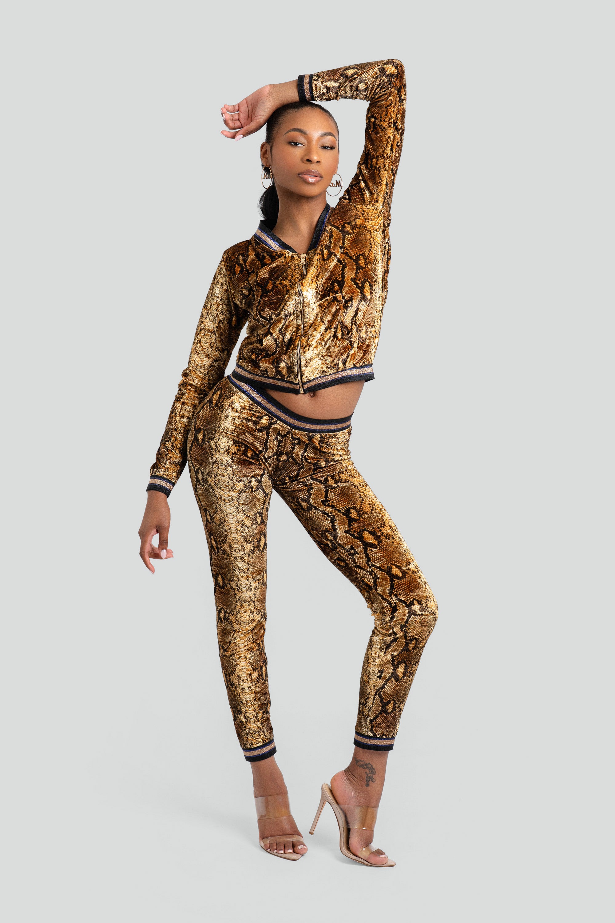 Woman wearing a gold snake print tracksuit on a white background