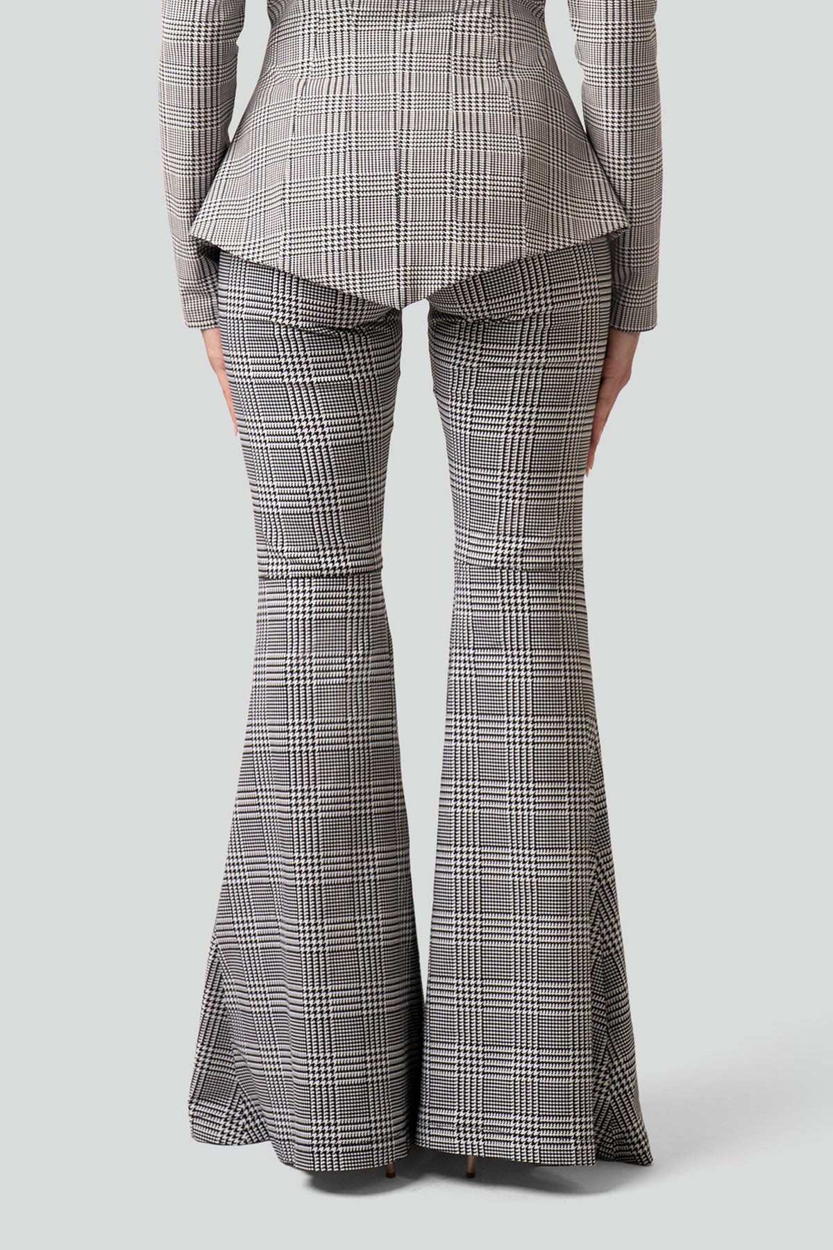 Oversized wide-leg black pants with structured pleating and a relaxed puddle hem styled for an editorial look