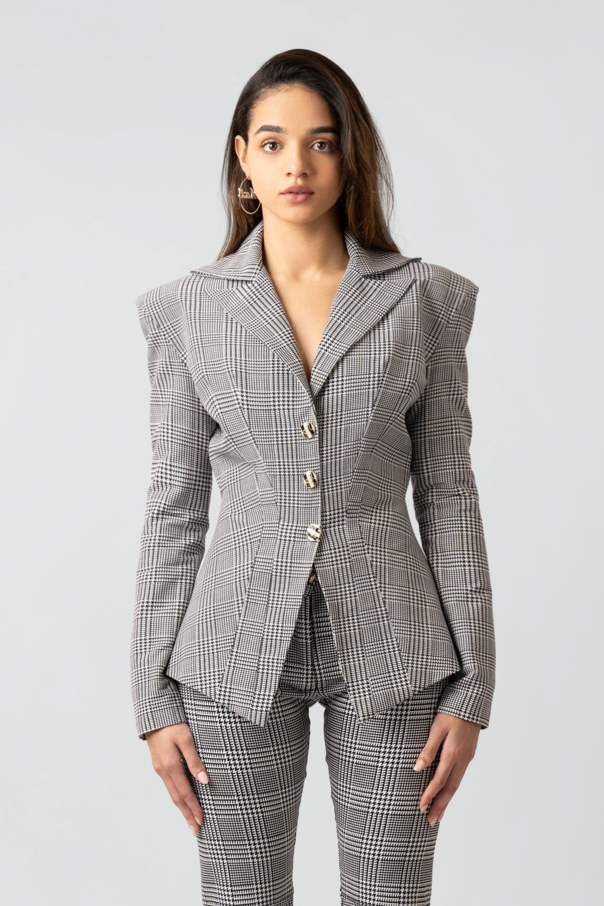 Woman wearing a gray plaid suit with flared pants on a white background