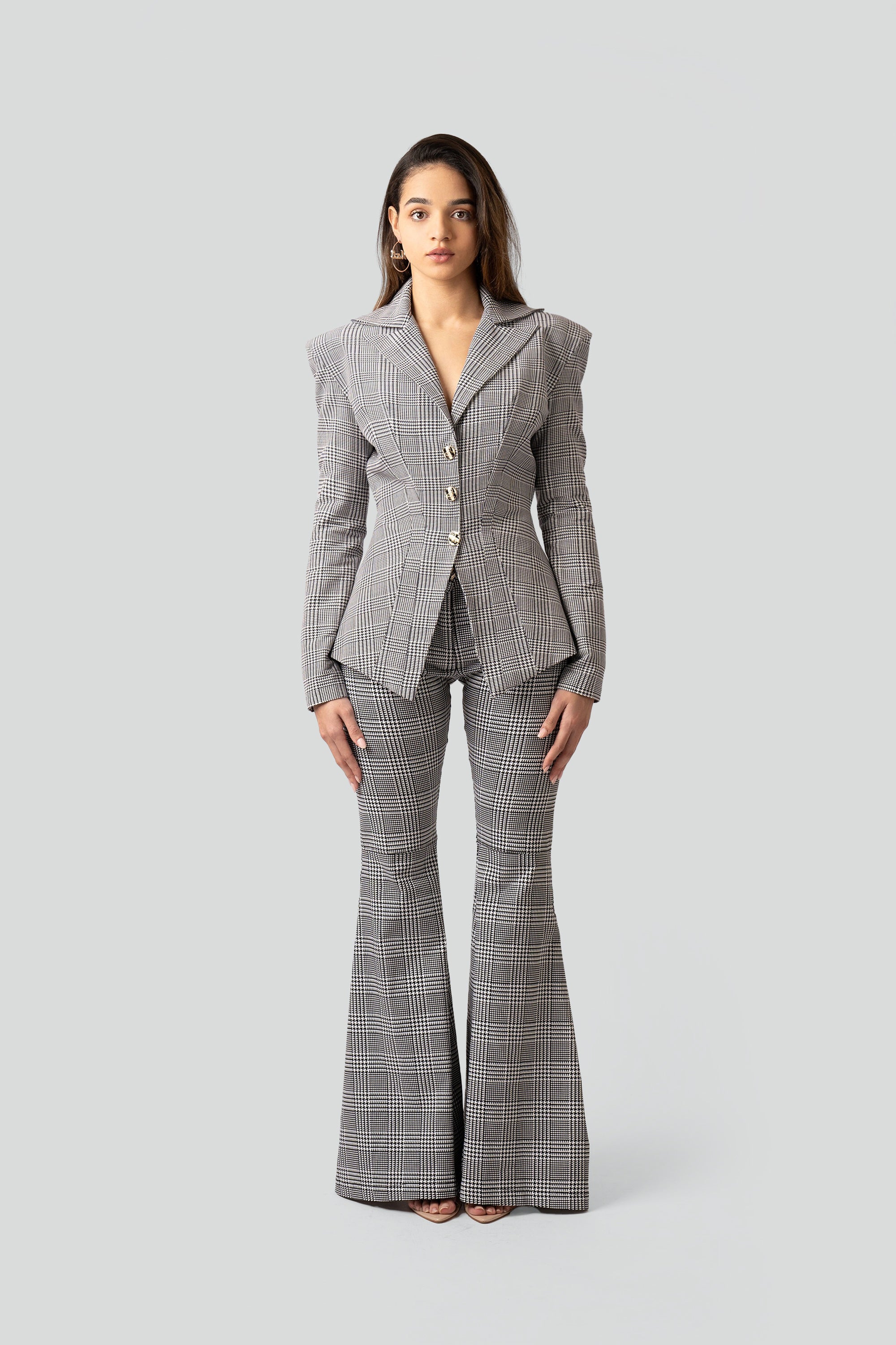 Woman wearing a gray plaid suit with flared pants on a white background