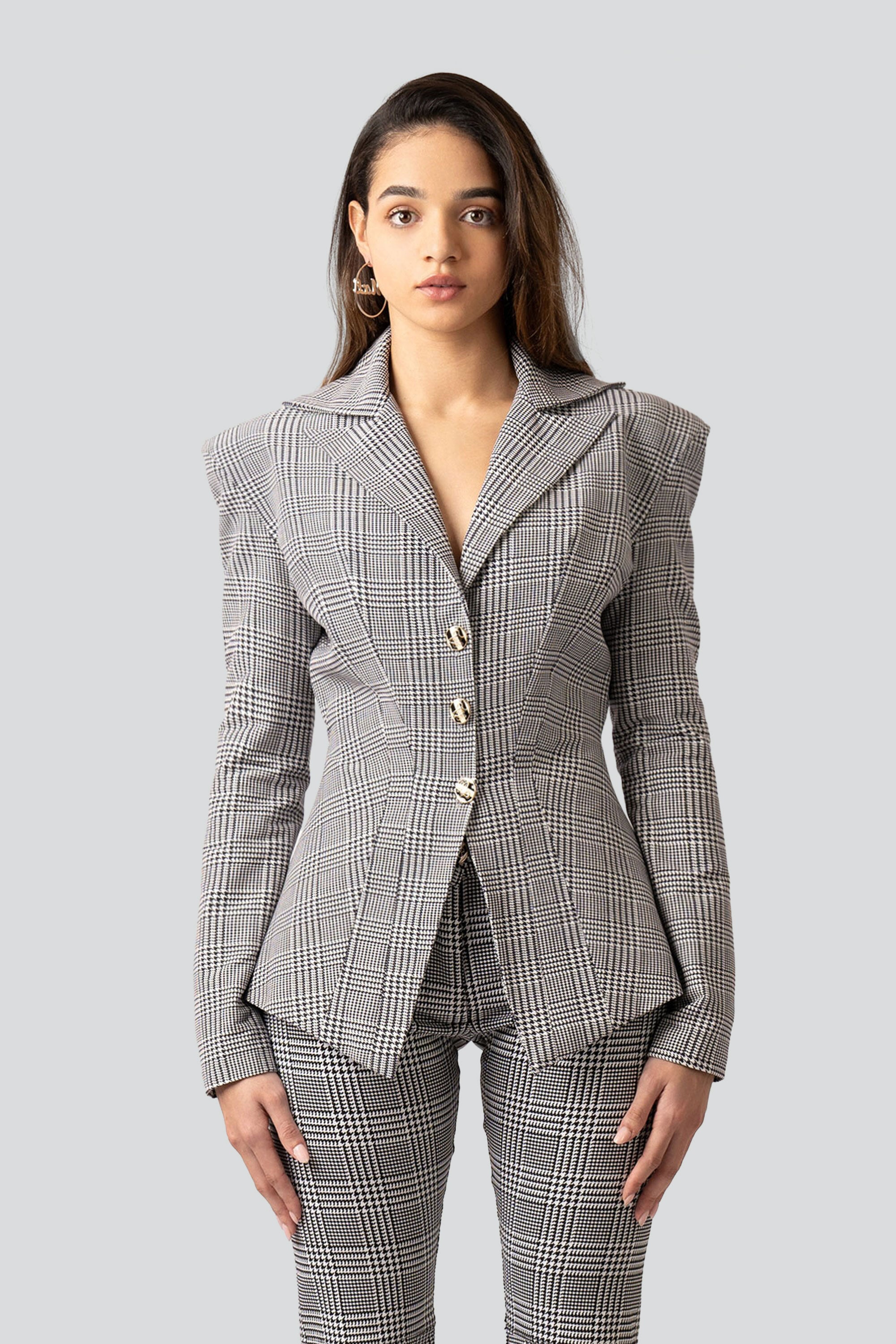 Woman wearing a gray plaid suit with flared pants on a white background