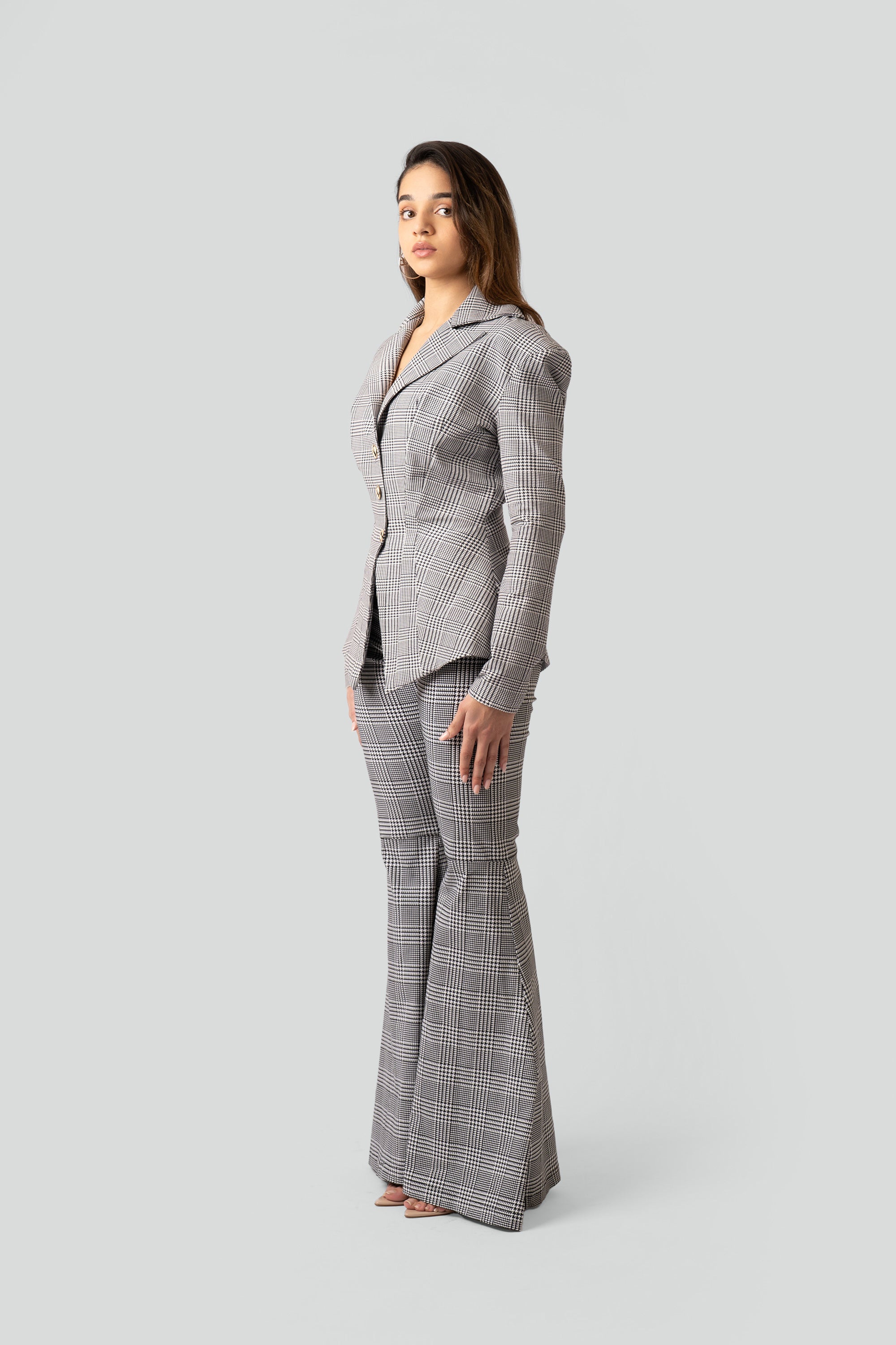 Woman wearing a gray plaid suit with flared pants on a white background