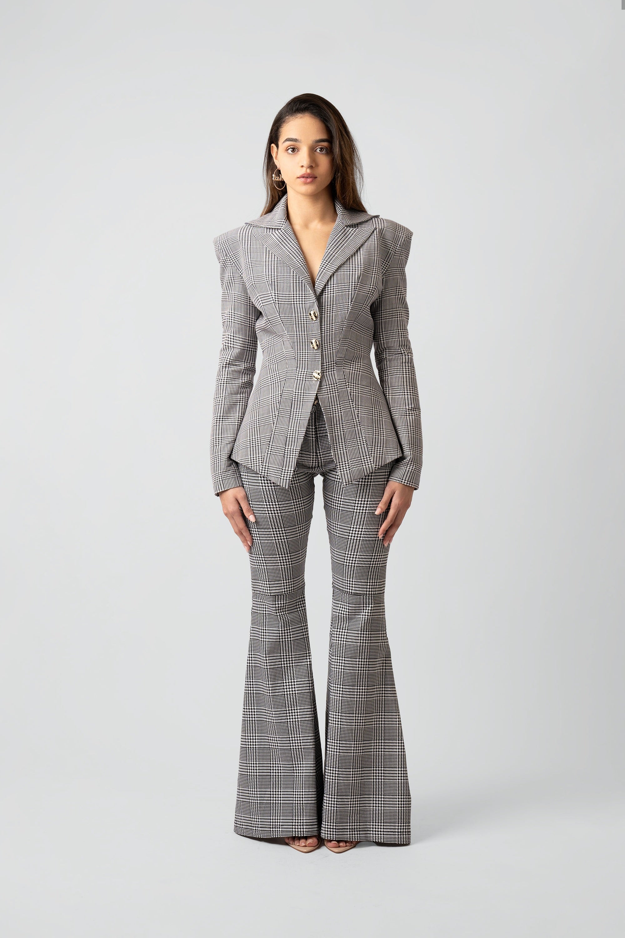 Woman wearing a gray plaid suit with flared pants on a white background