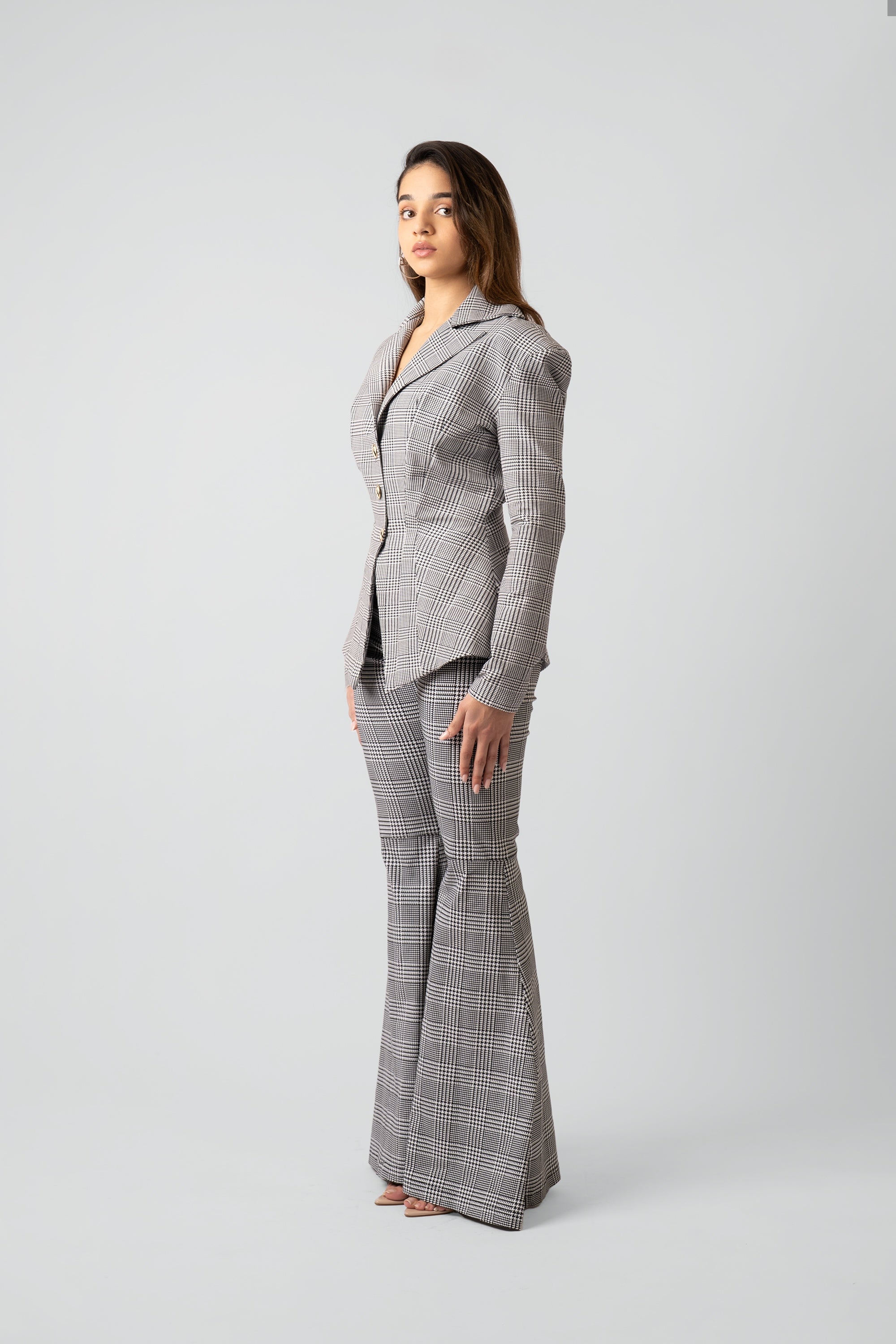 Woman wearing a gray plaid suit with flared pants on a white background