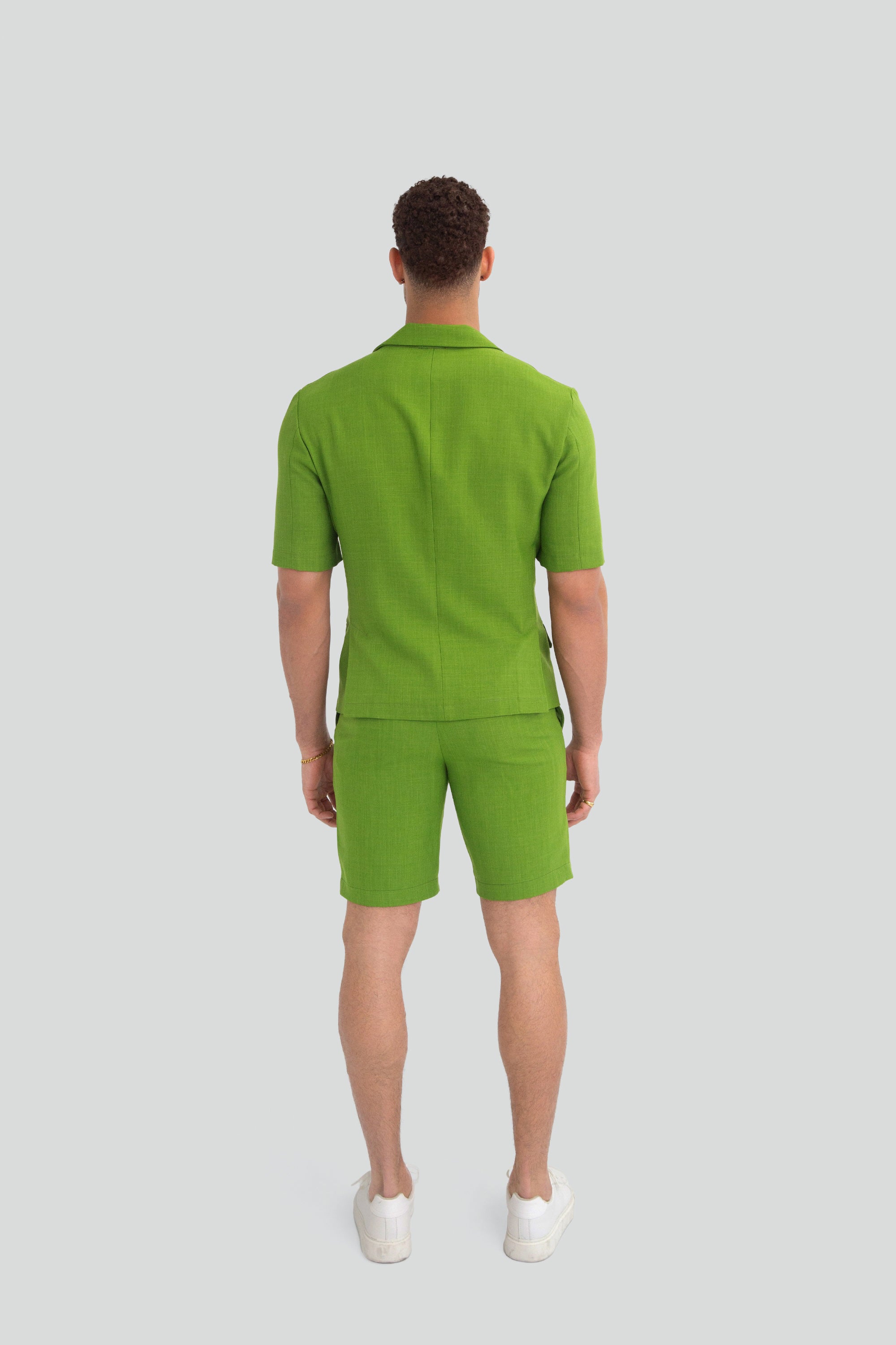 Man wearing a green short suit on a plain background