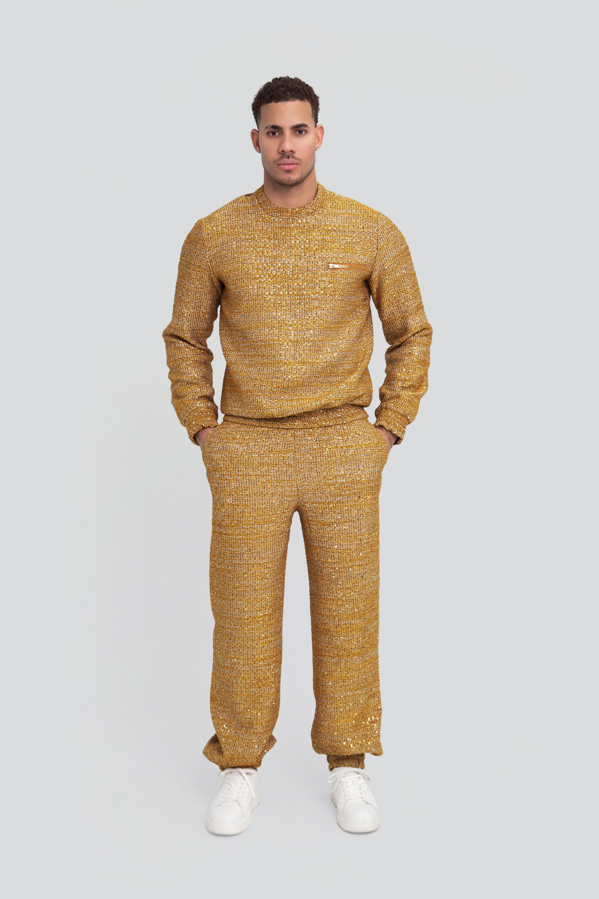 Man wearing a gold textured sweater and pants on a plain background
