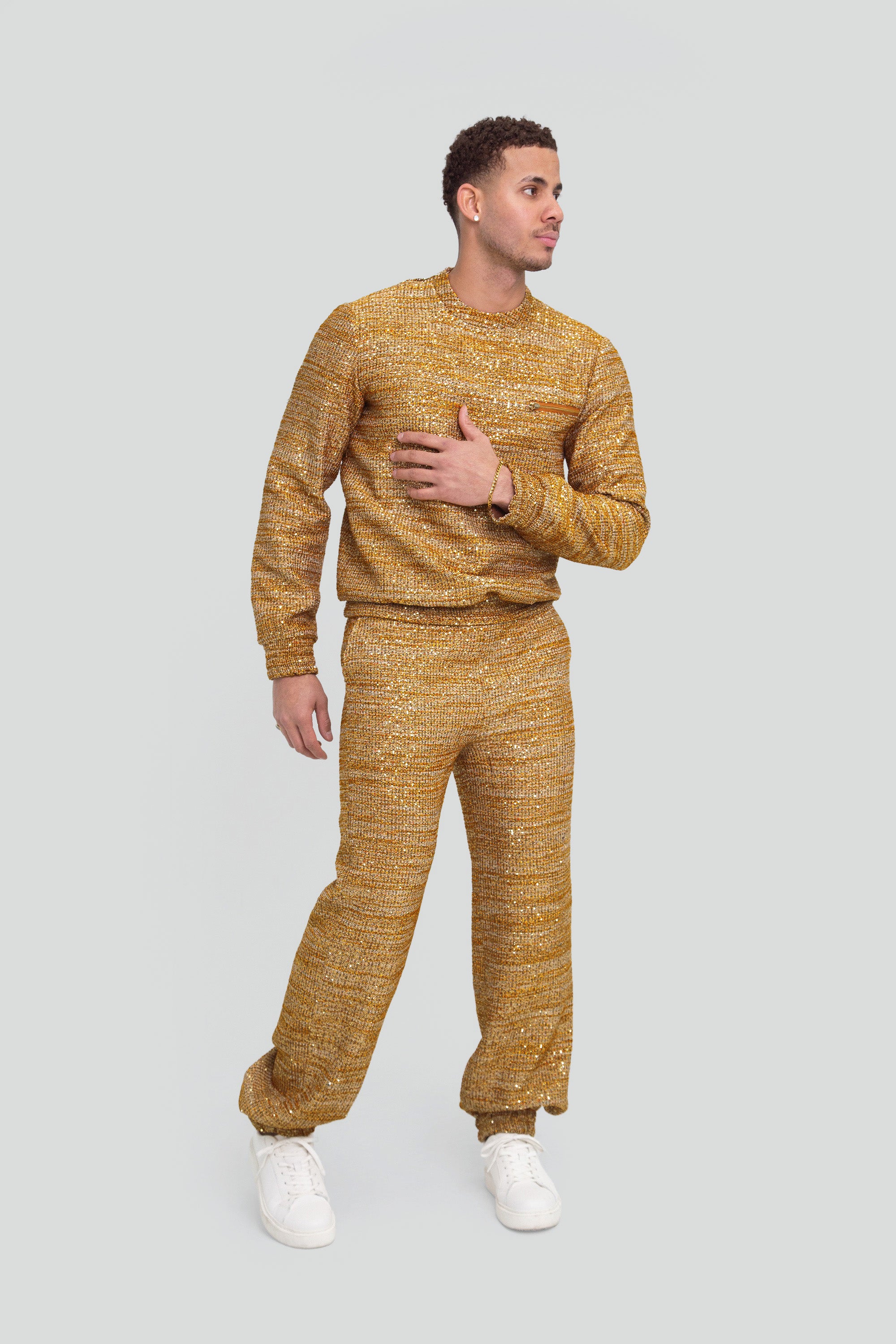 Man wearing a gold textured sweater and pants on a plain background