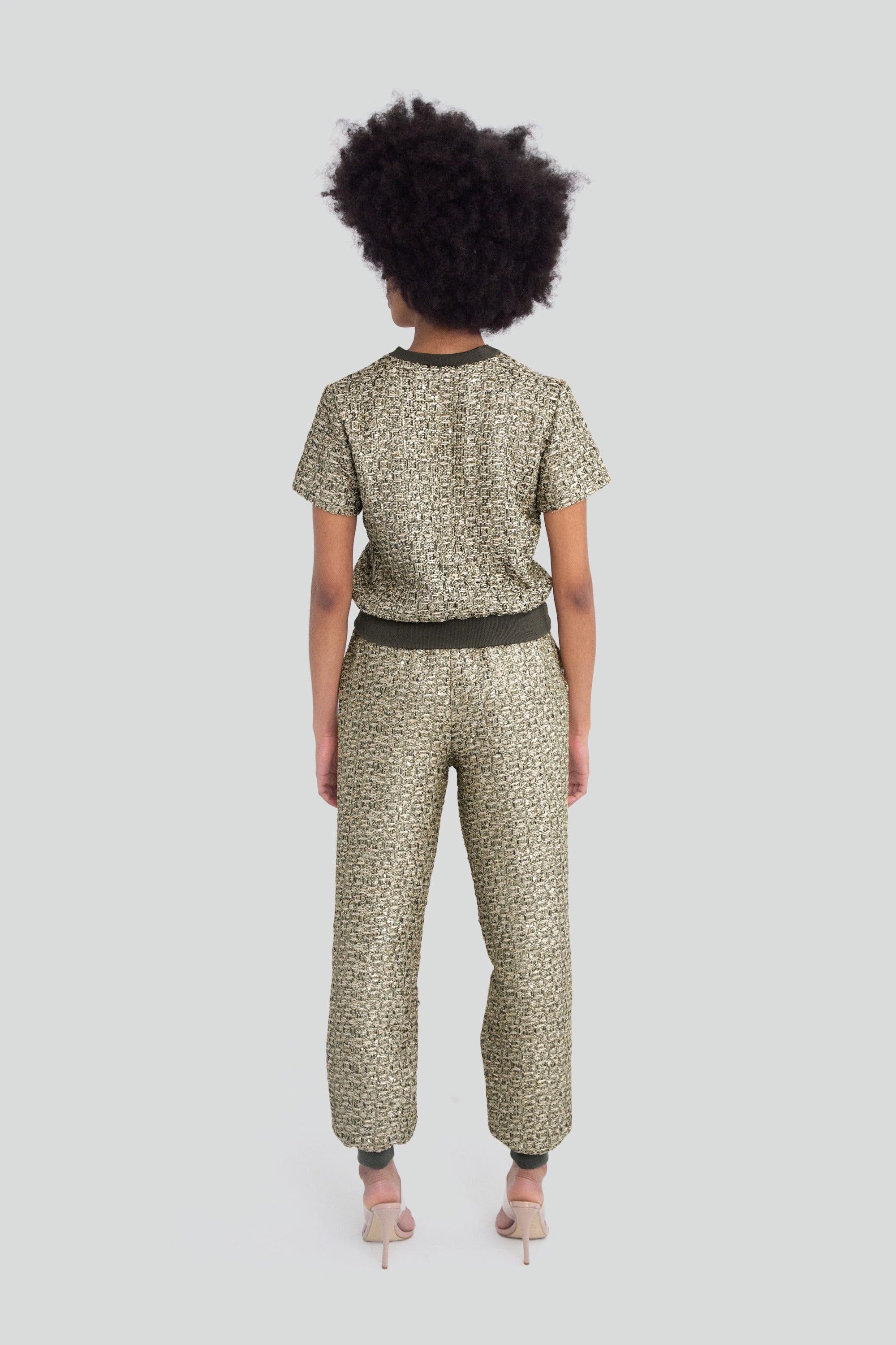 Woman wearing a green metallic textured outfit with short sleeves and pants on a plain background
