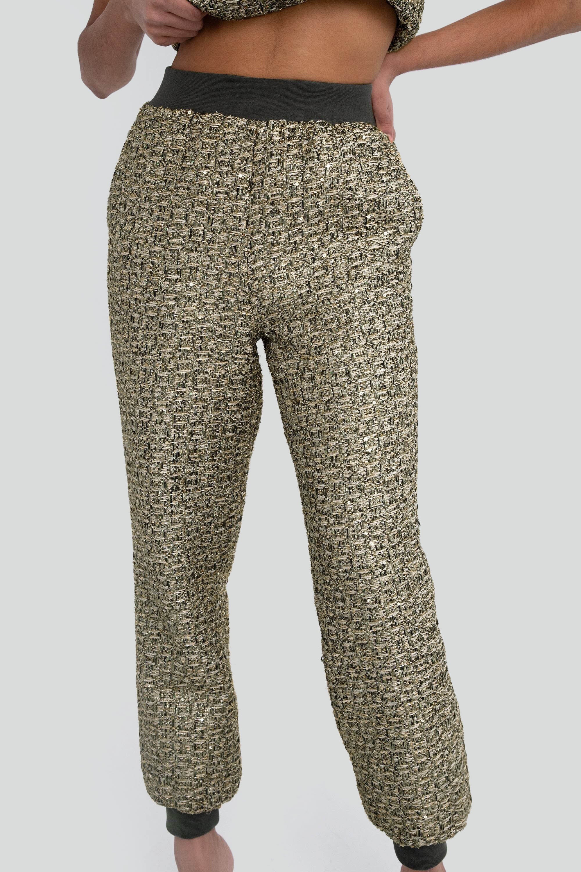Green metallic textured pants worn by a person on a plain background