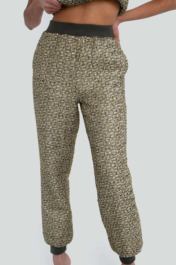  Model styling a luxury matching two piece shorts set in a shiny greenish gold metallic knitwear fabrication