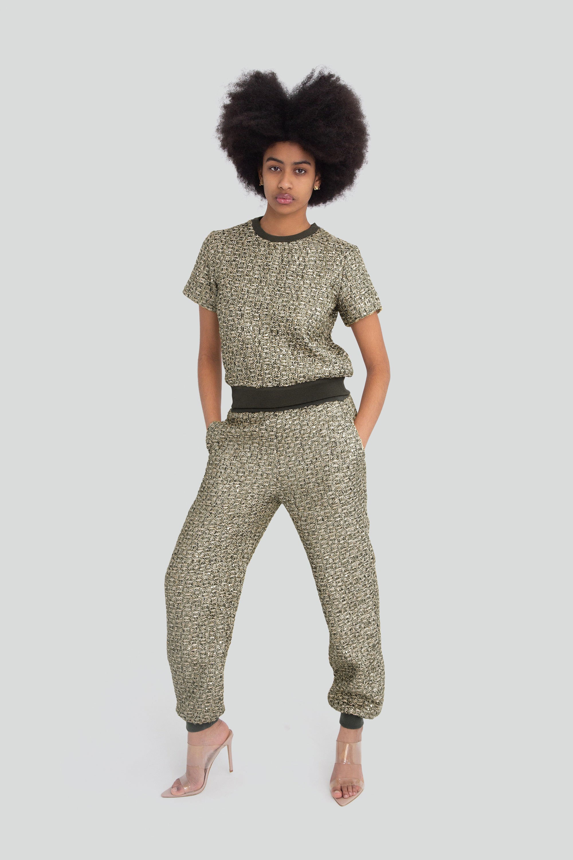 Woman wearing a green metallic textured outfit with short sleeves and pants on a plain background