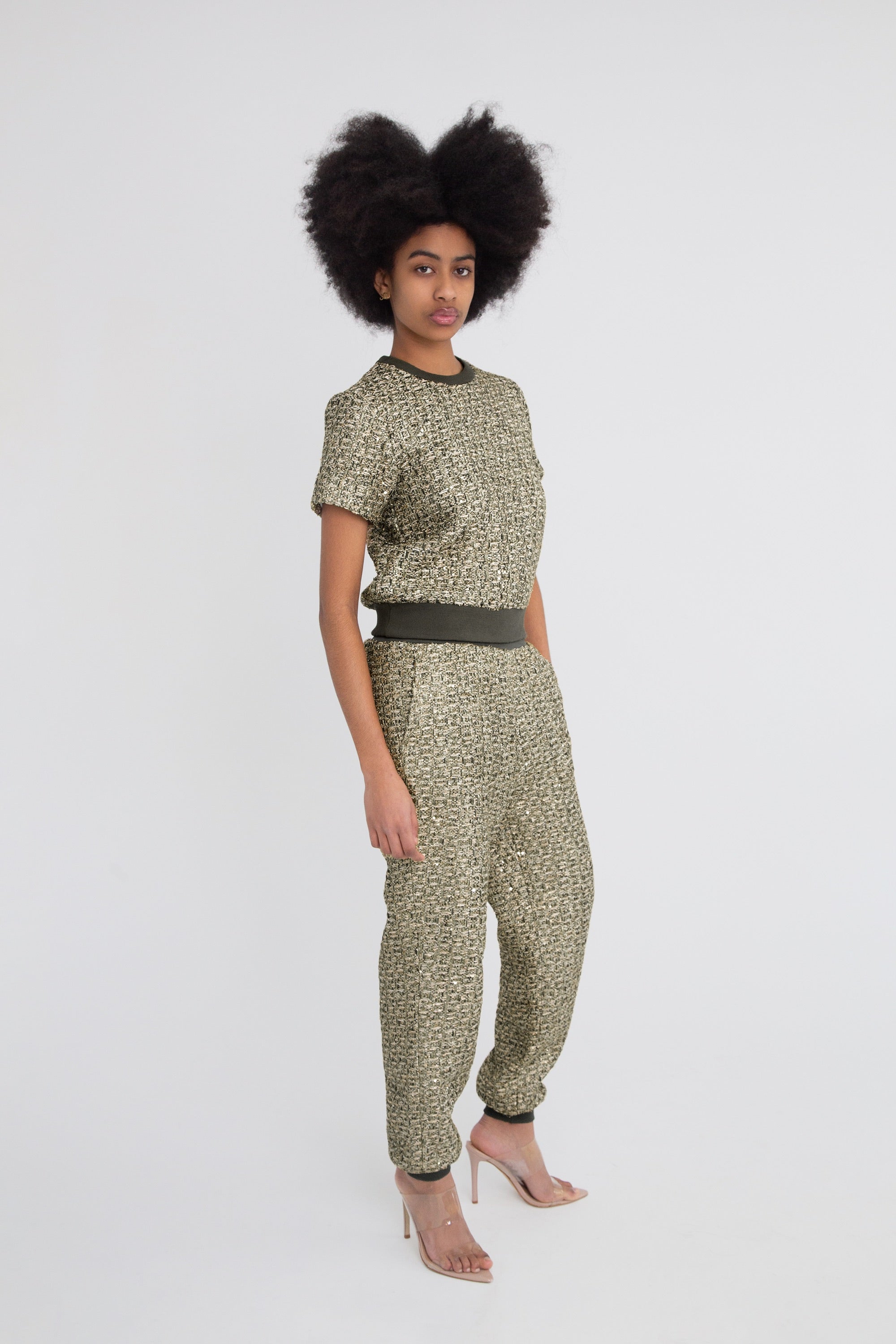 Woman wearing a green metallic textured outfit with short sleeves and pants on a plain background