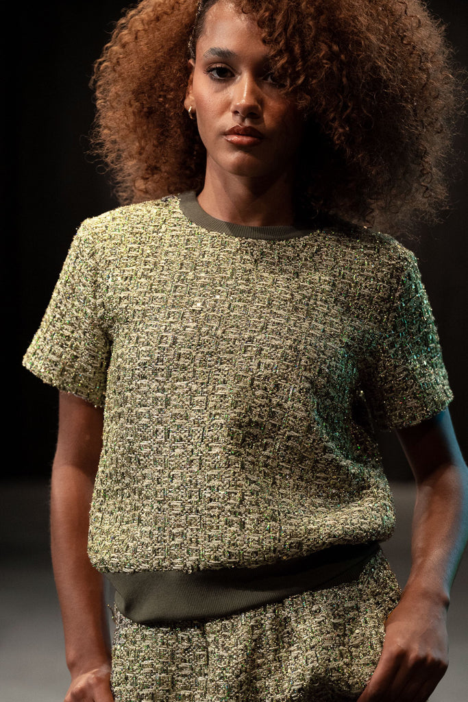Woman wearing a textured green outfit against a dark background