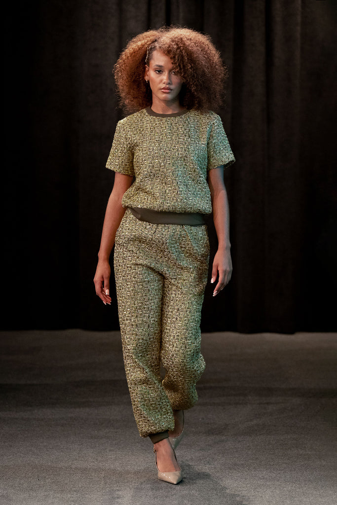 Model wearing a green patterned outfit against a dark background