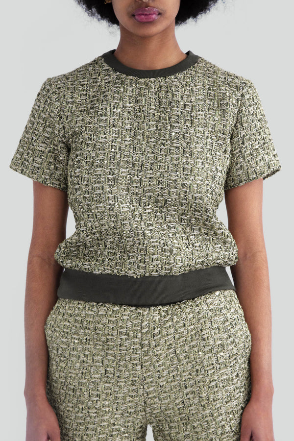 Greenish gold metallic tweed top worn by a women, featuring a relaxed fit short sleeve crewneck sweater cut woven with shiny silver lurex threads