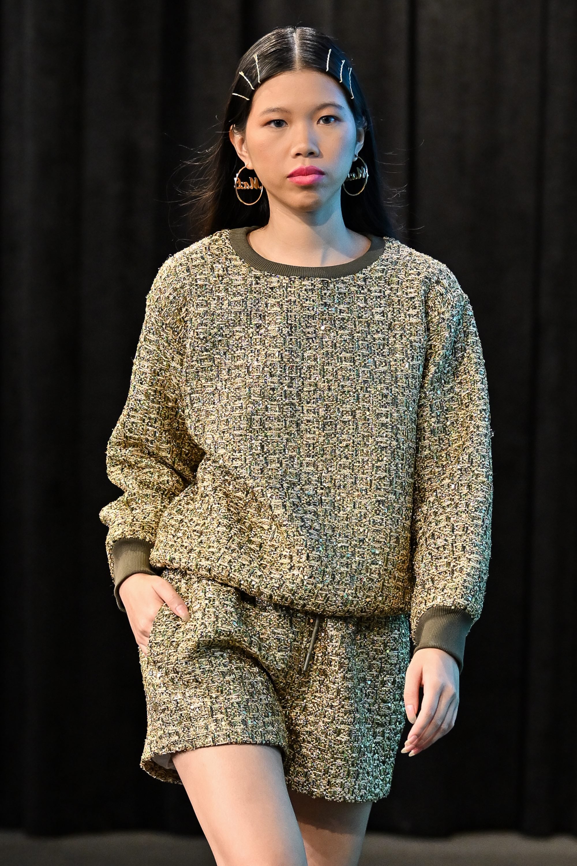 Person wearing a textured sweater and shorts set against a black background