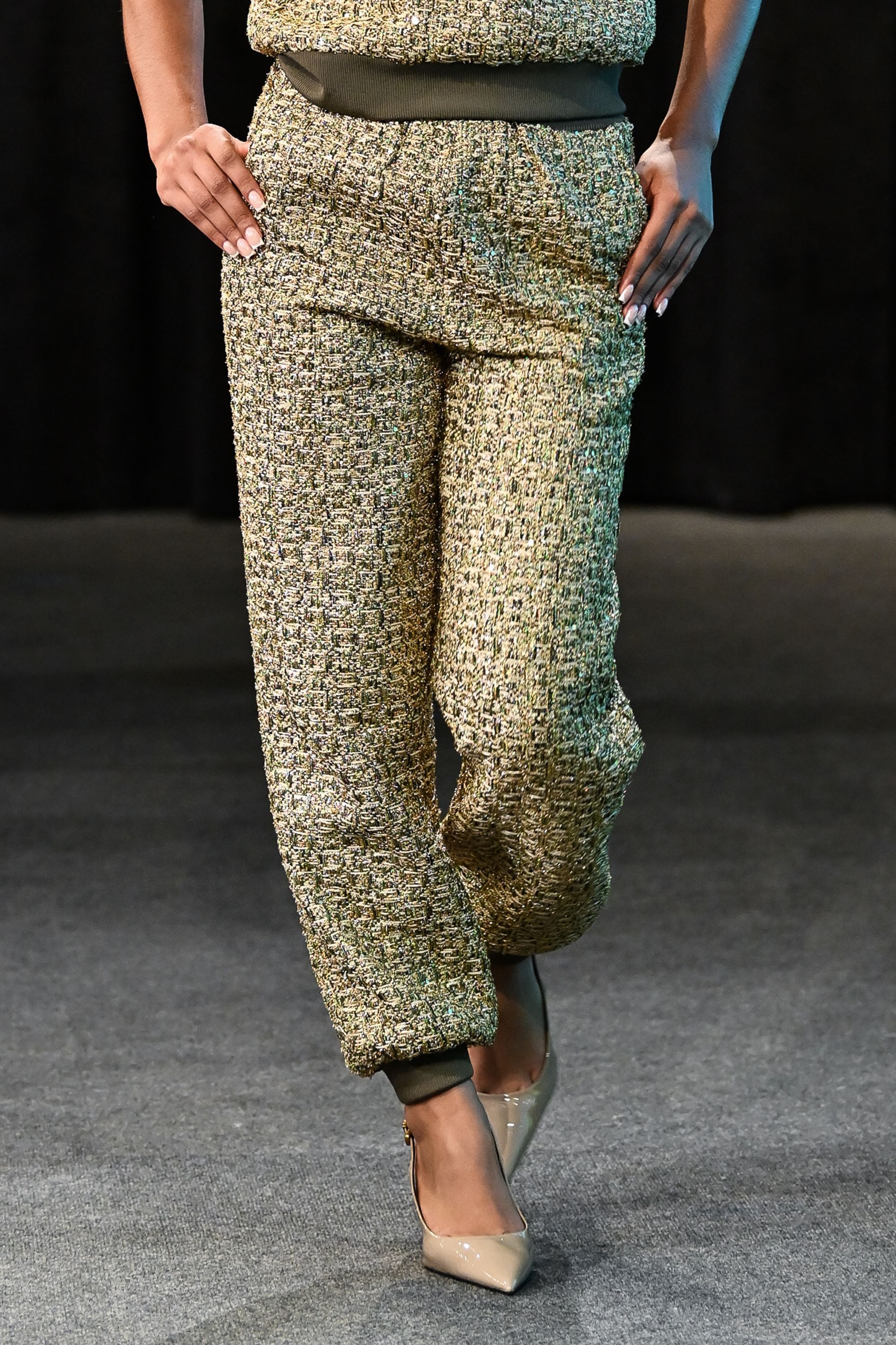 Model wearing a green patterned outfit against a dark background