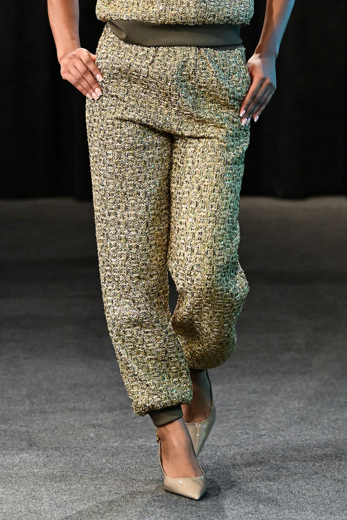 Model wearing a green patterned outfit against a dark background