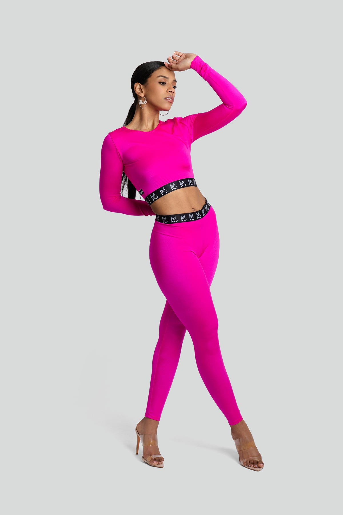 A vibrant hot pink long-sleeve top and matching pant lounge set styled for an active, athletic look