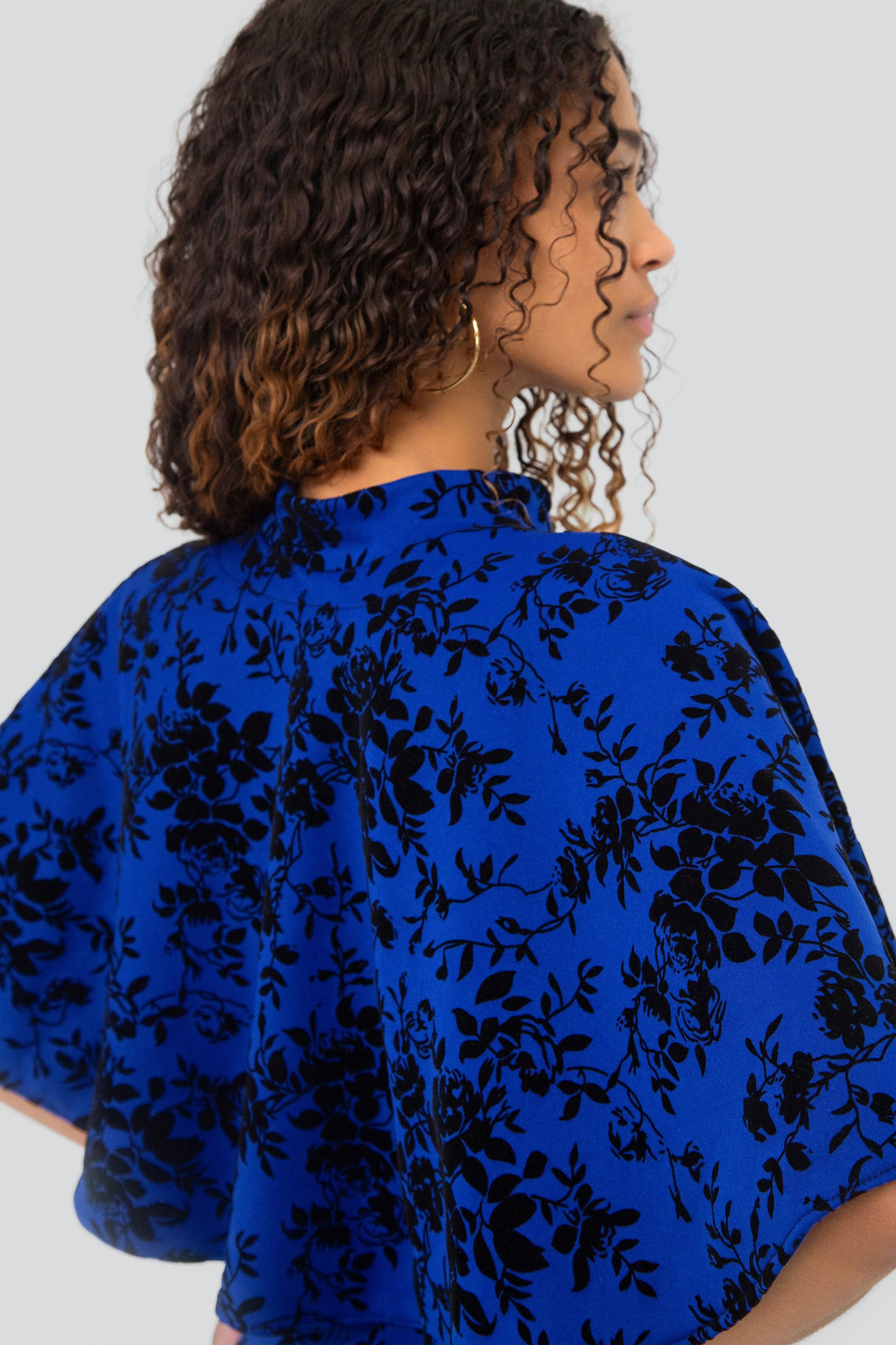Woman wearing a blue floral outfit on a plain background