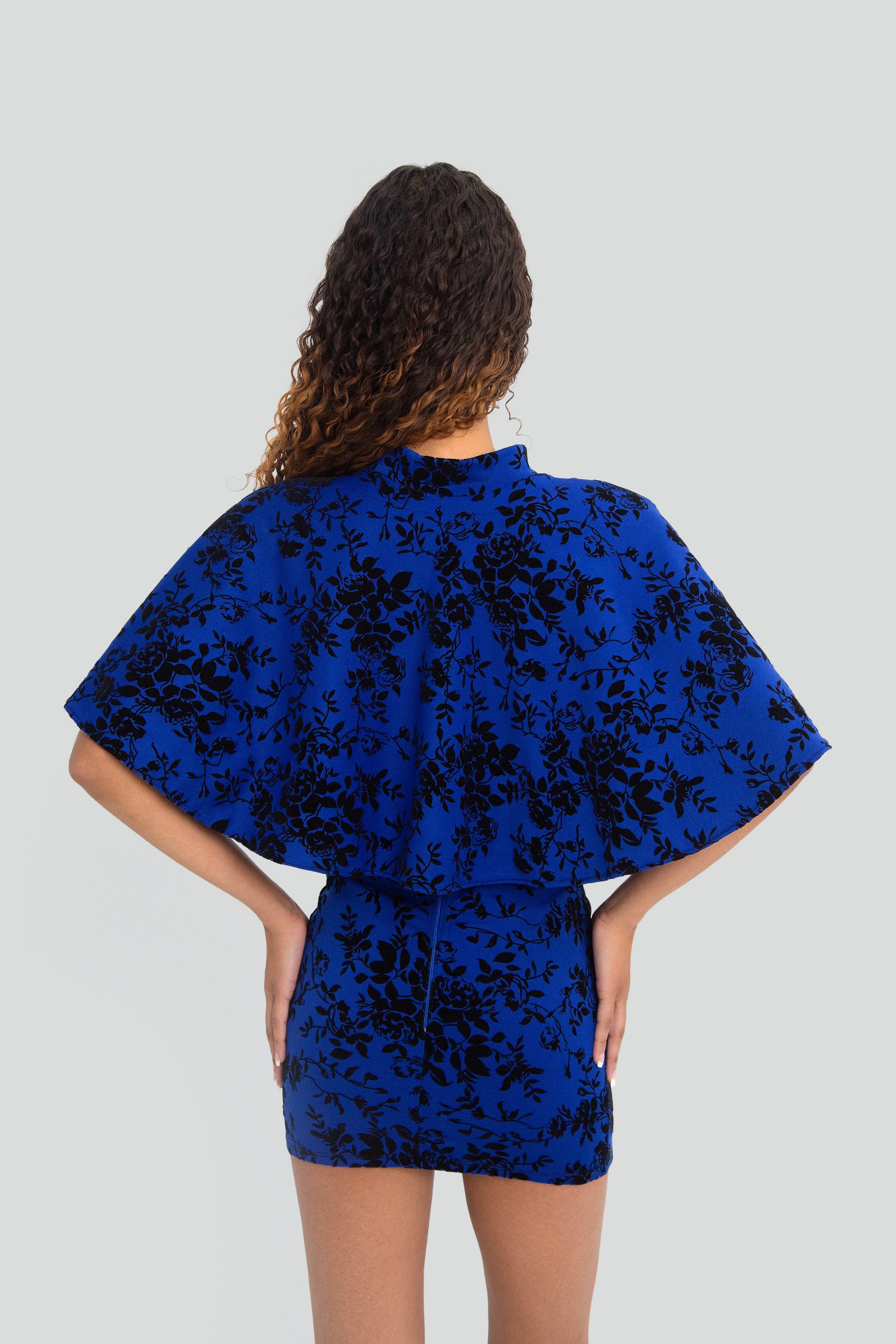 Woman wearing a blue floral outfit on a plain background