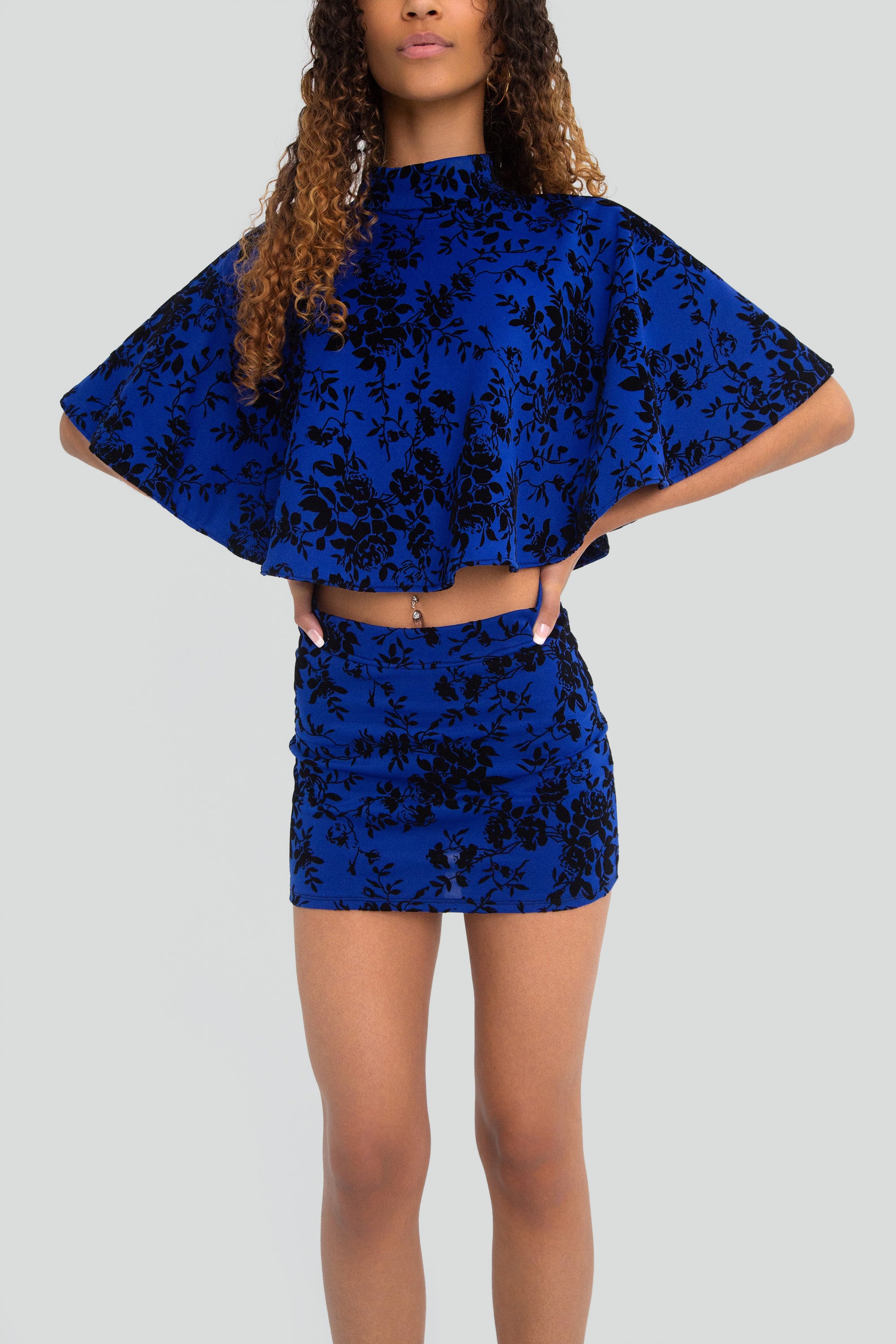 Woman wearing a blue floral outfit on a plain background