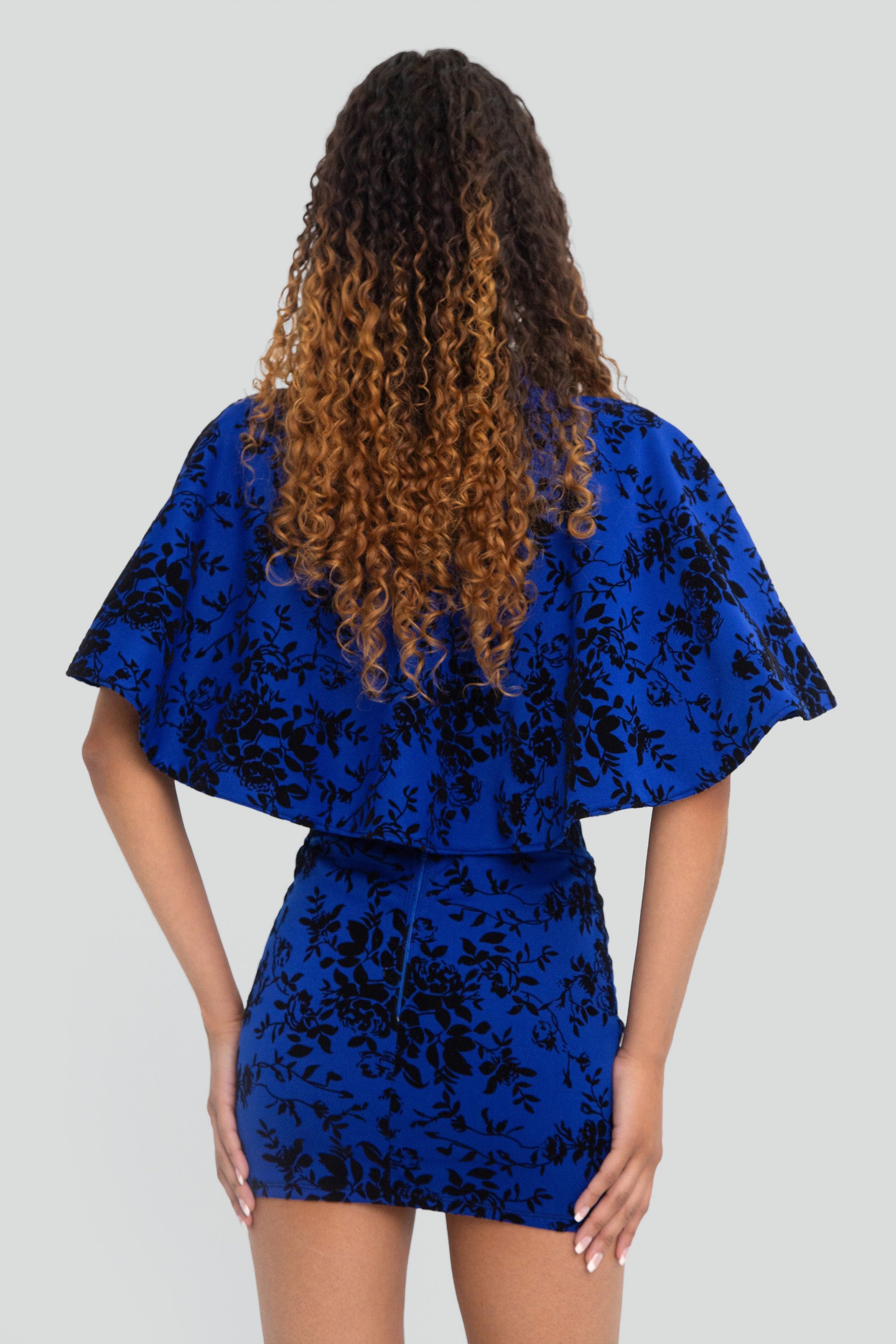 Woman wearing a blue floral outfit on a plain background