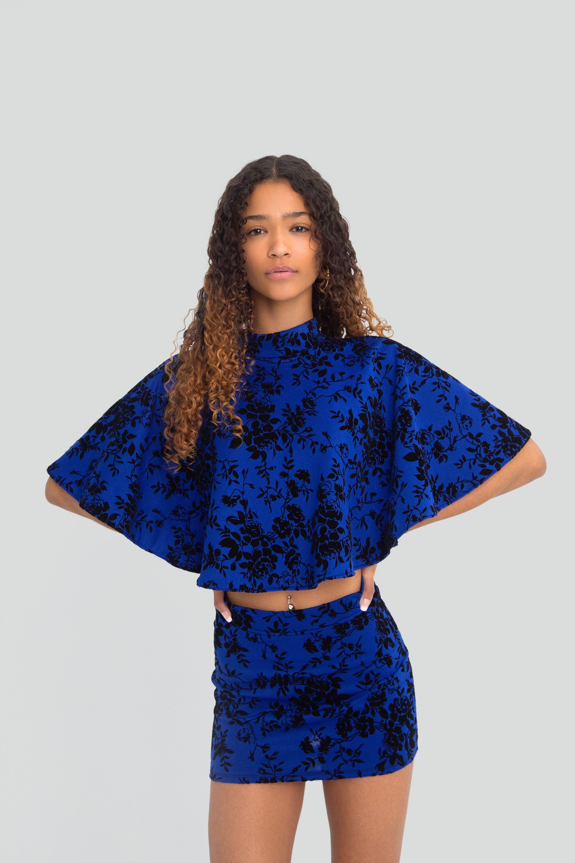 Woman wearing a blue floral outfit on a plain background