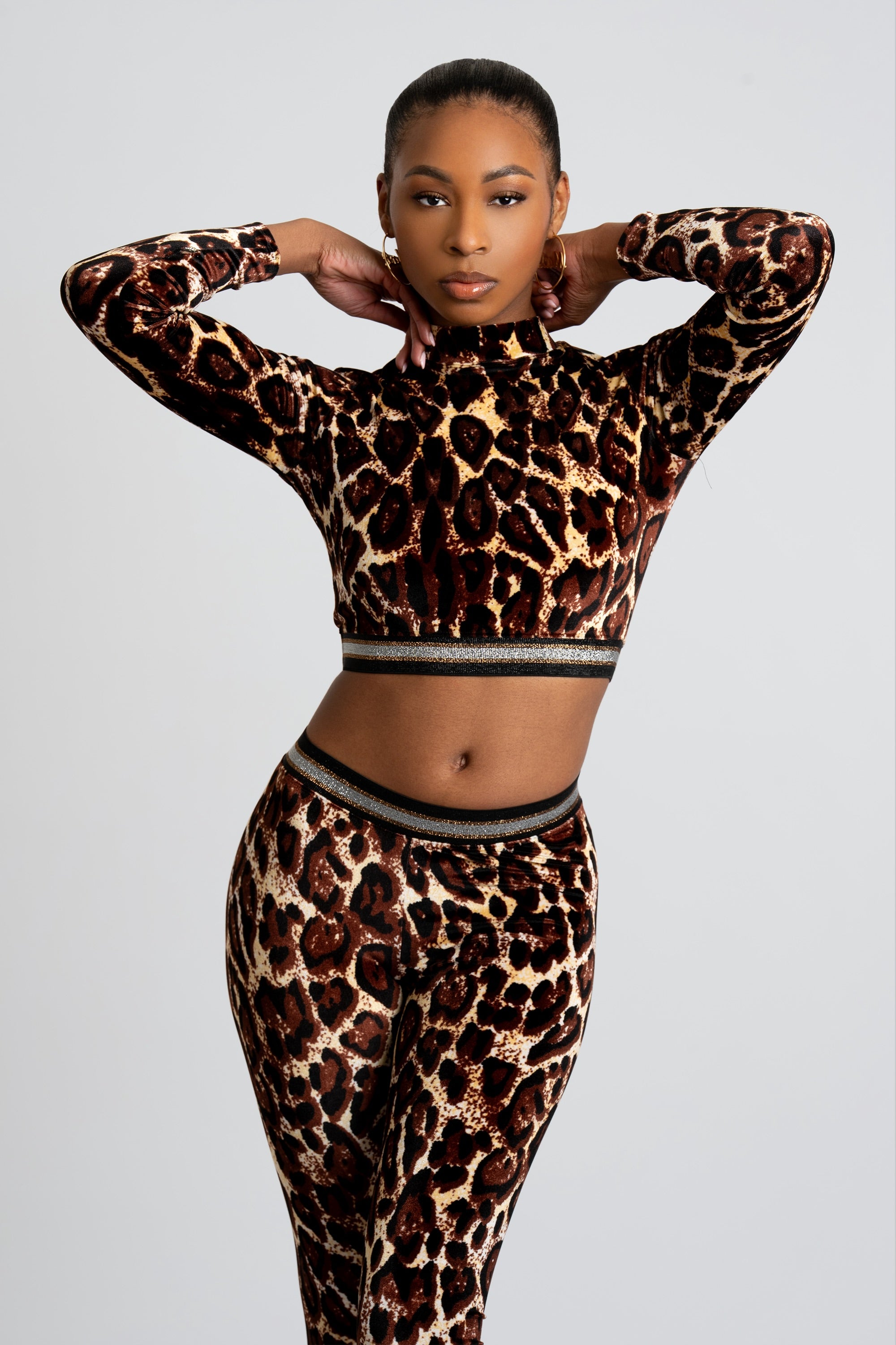 Woman wearing a velour two-piece cheetah print outfit on a white background