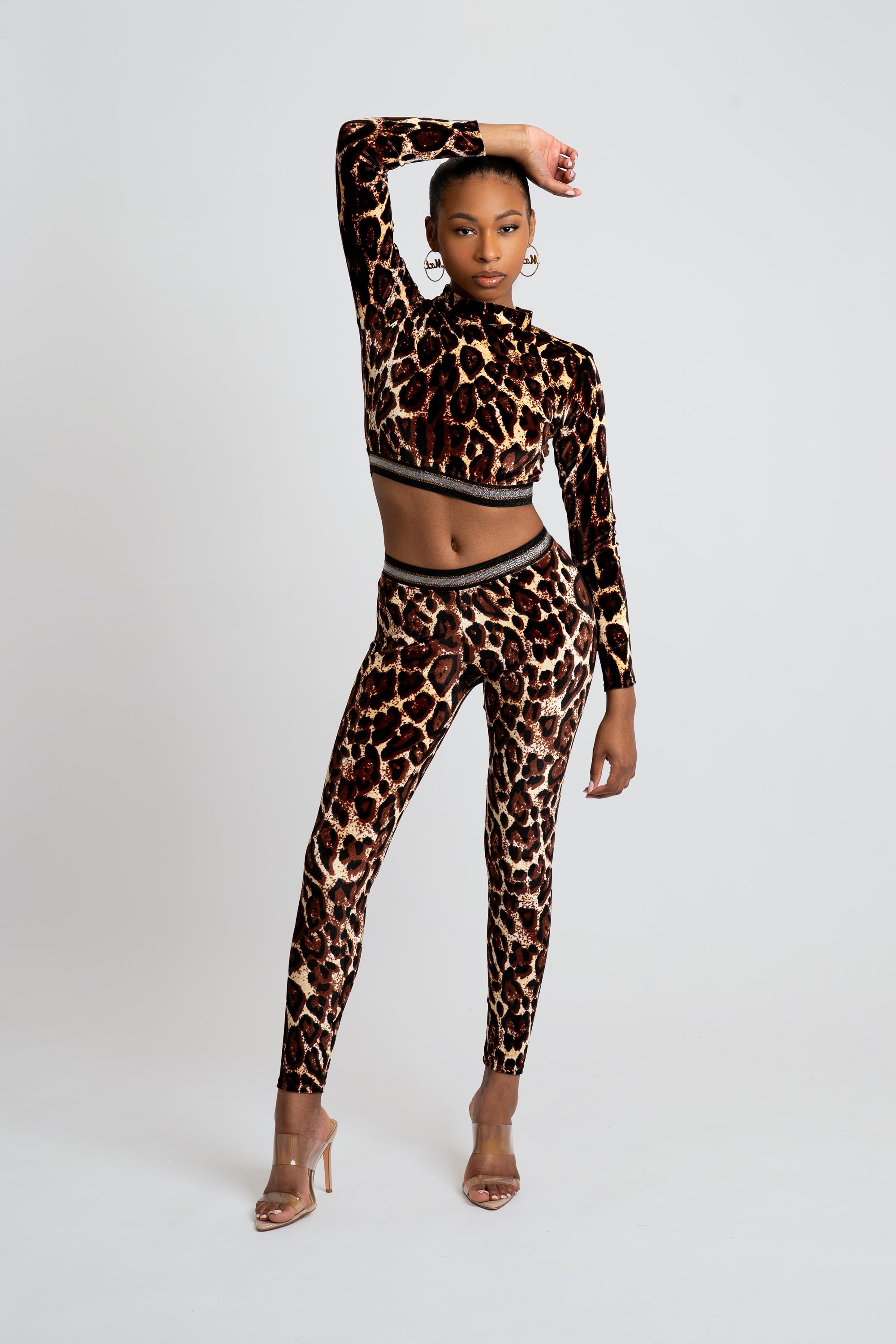 Woman wearing a velour two-piece cheetah print outfit on a white background
