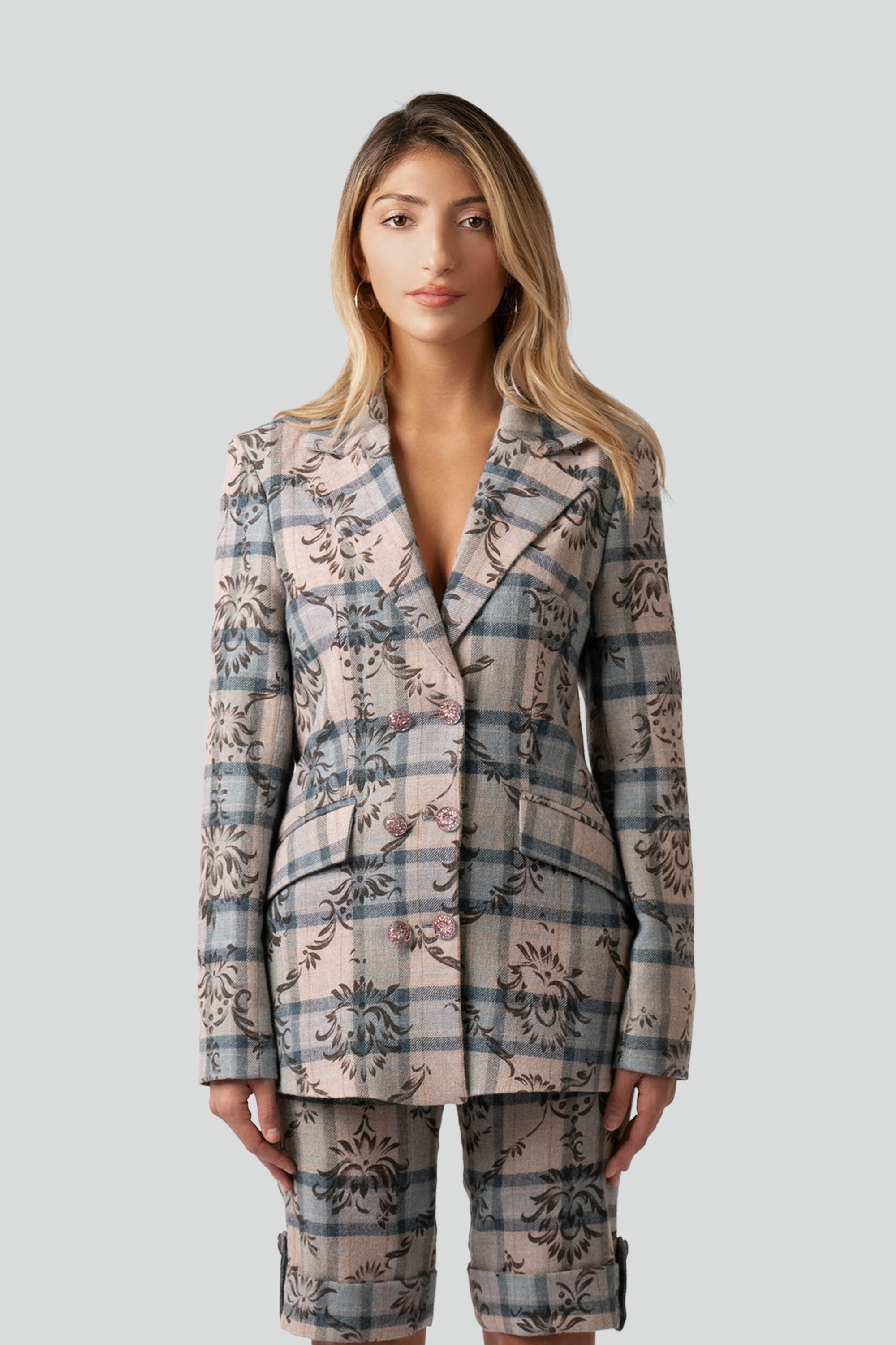 Woman wearing a floral and plaid patterned blazer and matching shorts on a white background