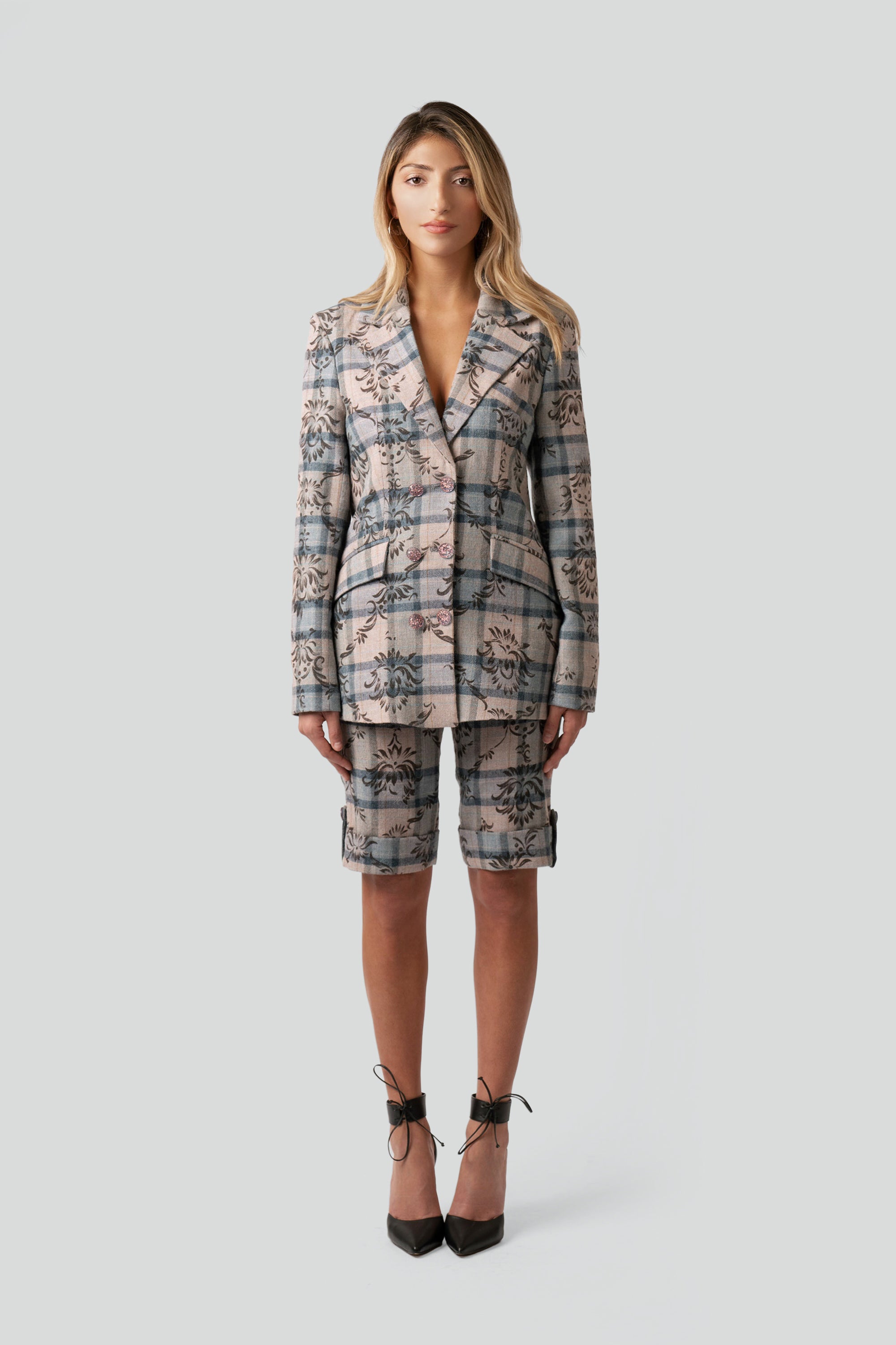 Woman wearing a floral and plaid patterned blazer and matching shorts on a white background