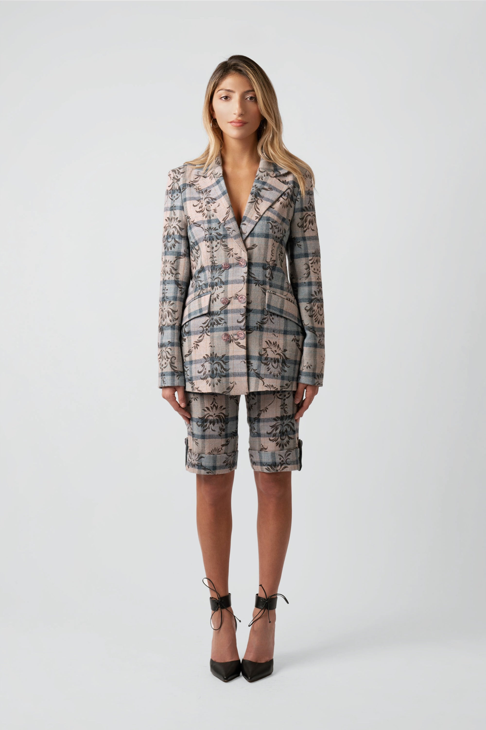 Woman wearing a floral and plaid patterned blazer and matching shorts on a white background