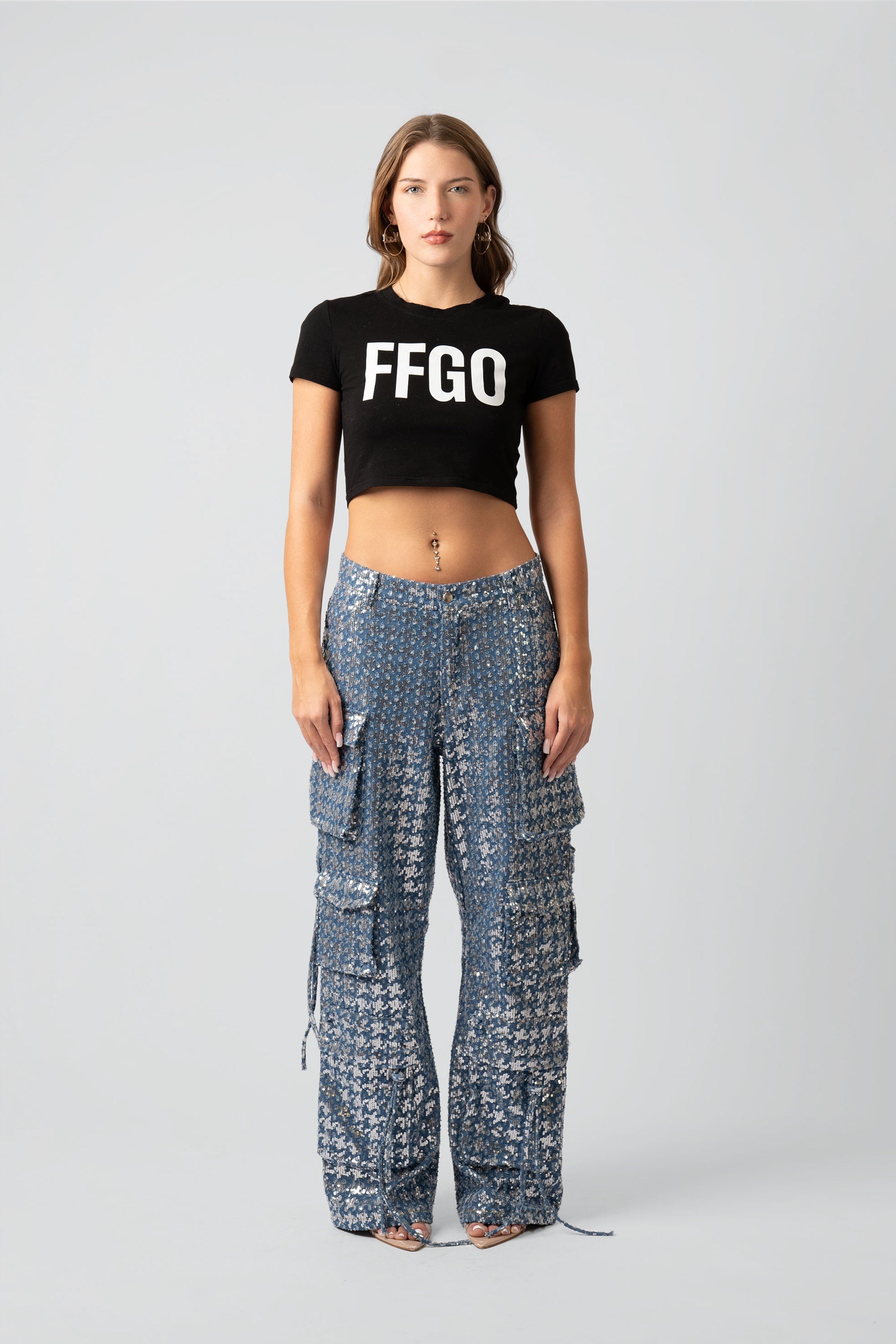 Woman wearing a black 'FFGO' crop top and patterned pants on a white background