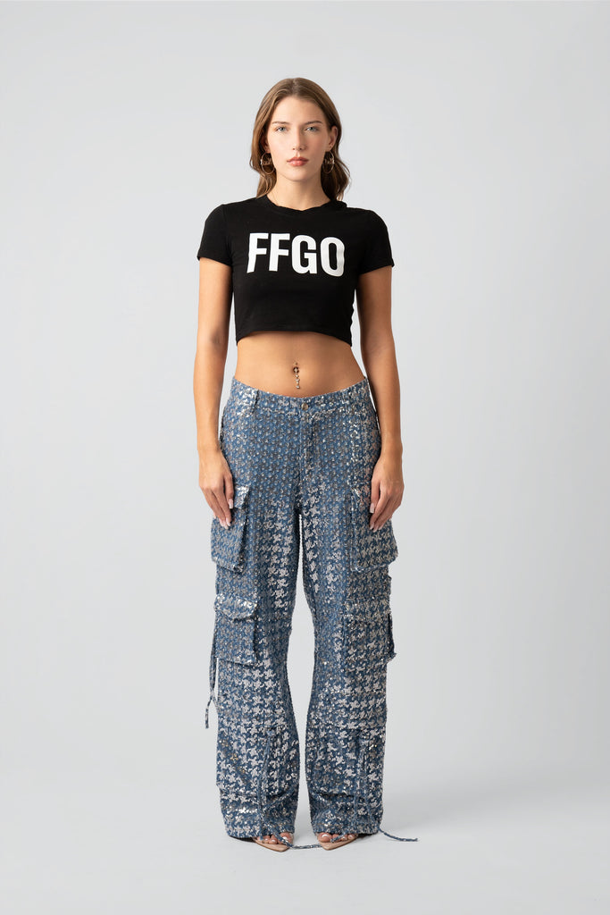 Woman wearing a black 'FFGO' crop top and patterned pants on a white background