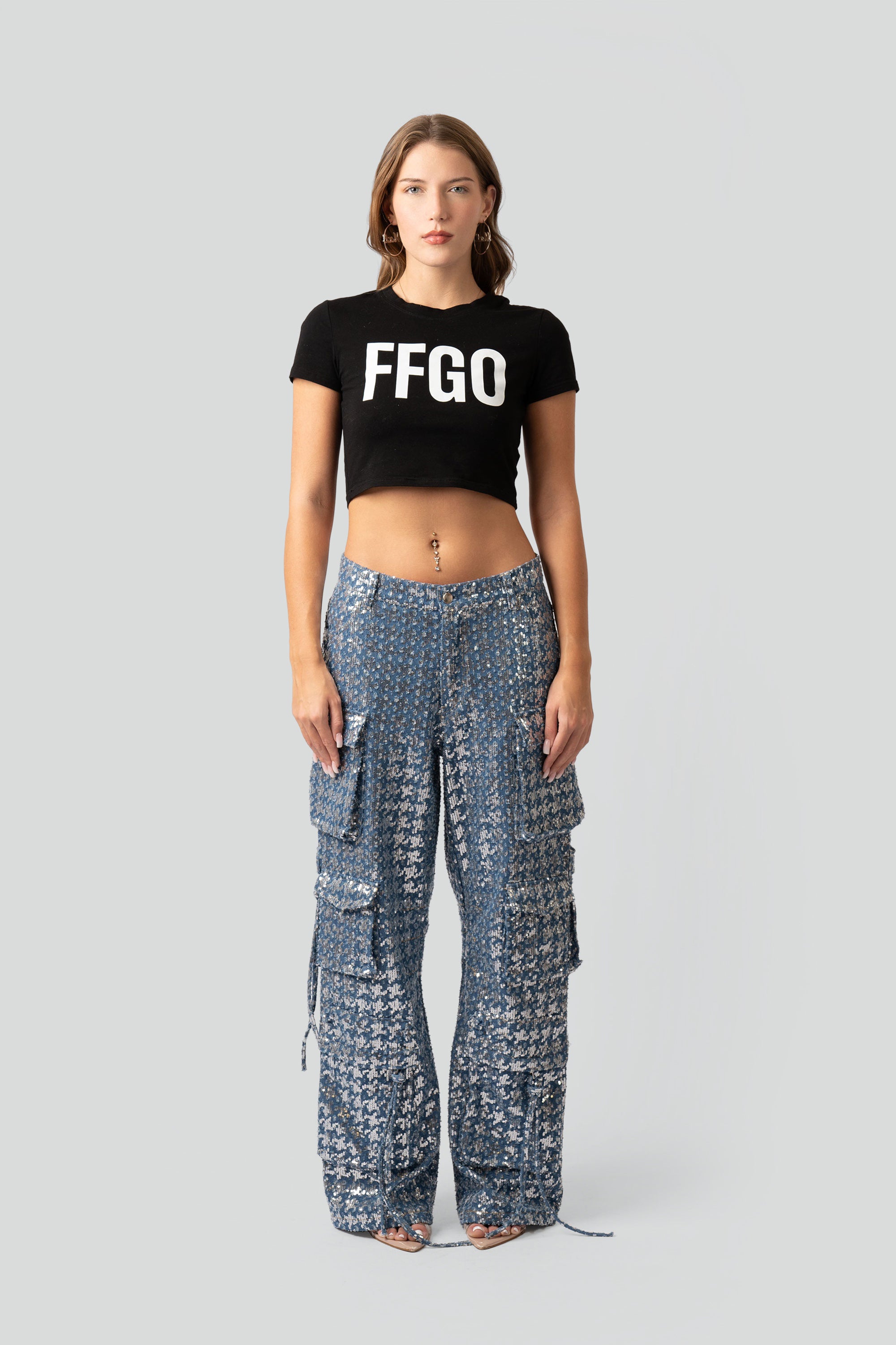 Woman wearing a black 'FFGO' crop top and patterned pants on a white background