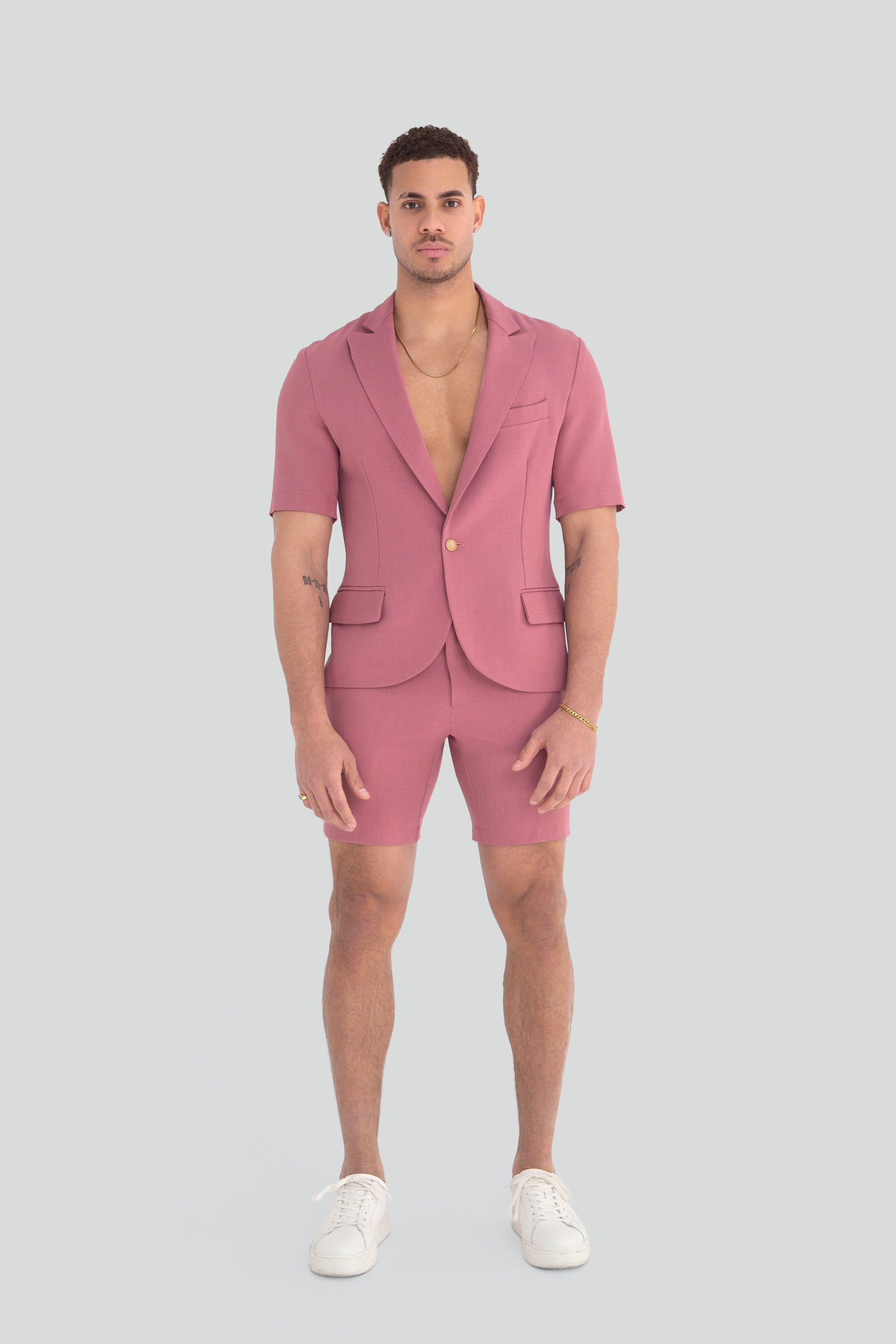 Man wearing a pink short suit on a plain background