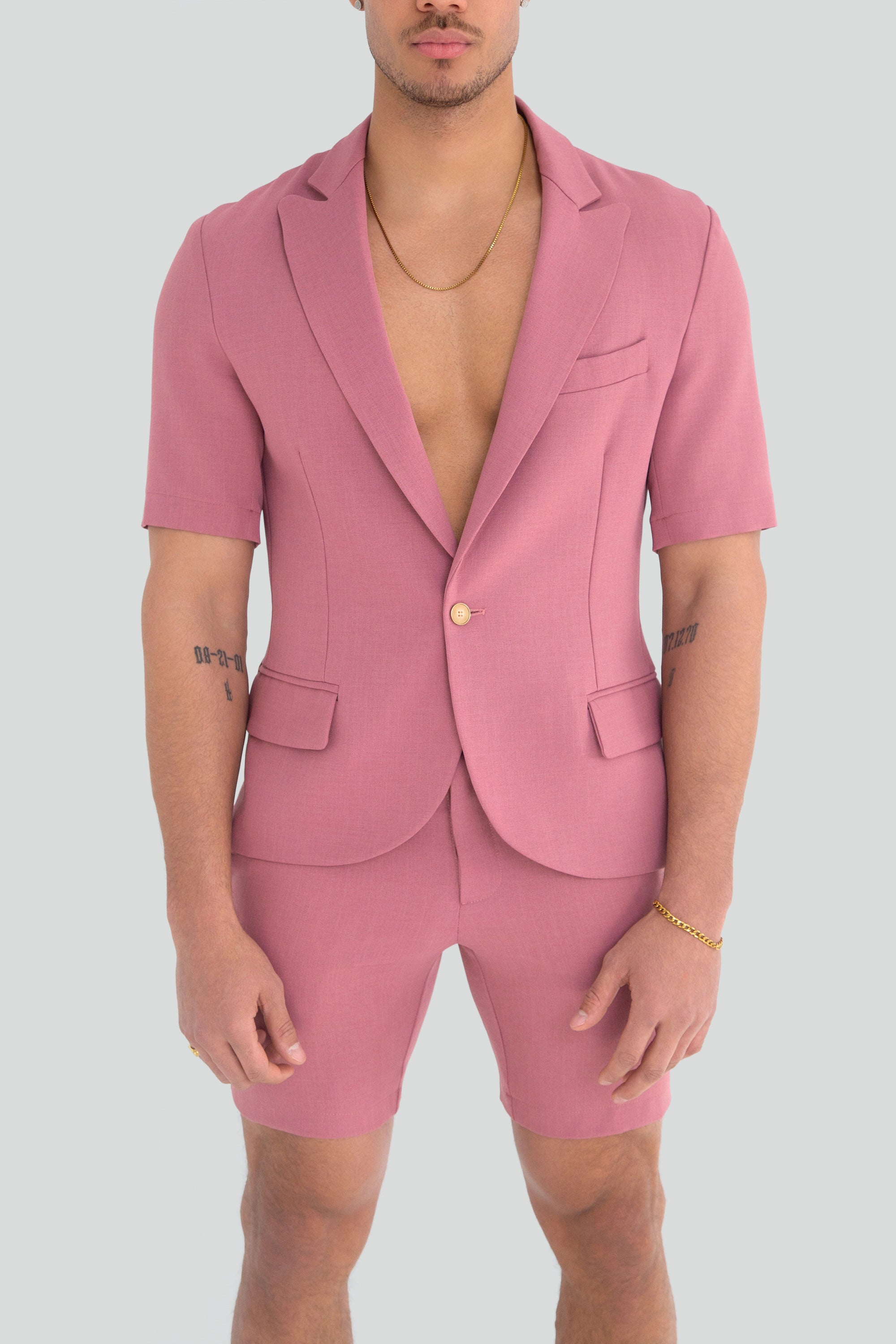 Man wearing a pink short suit on a plain background