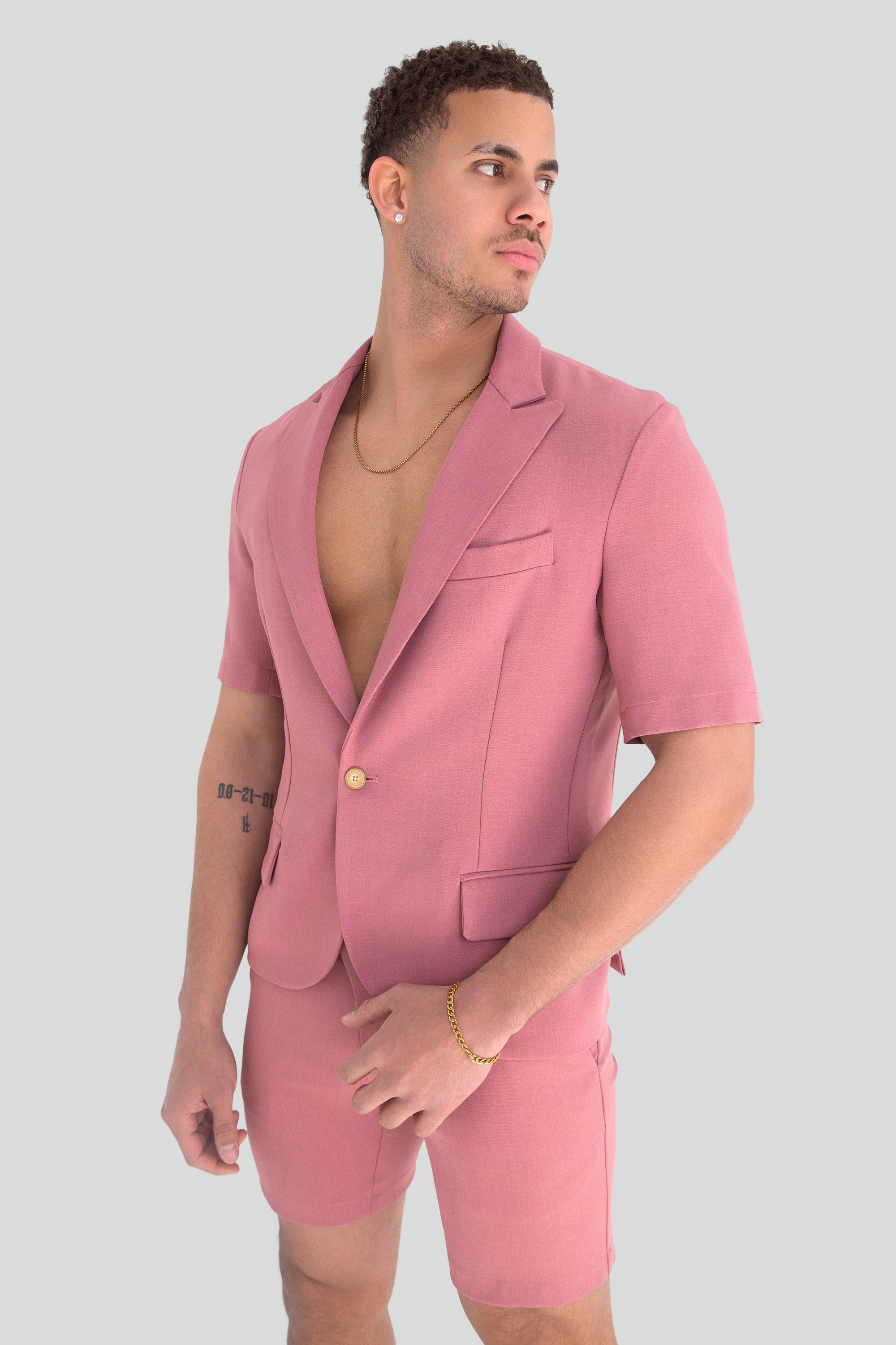 Man wearing a pink short suit on a plain background