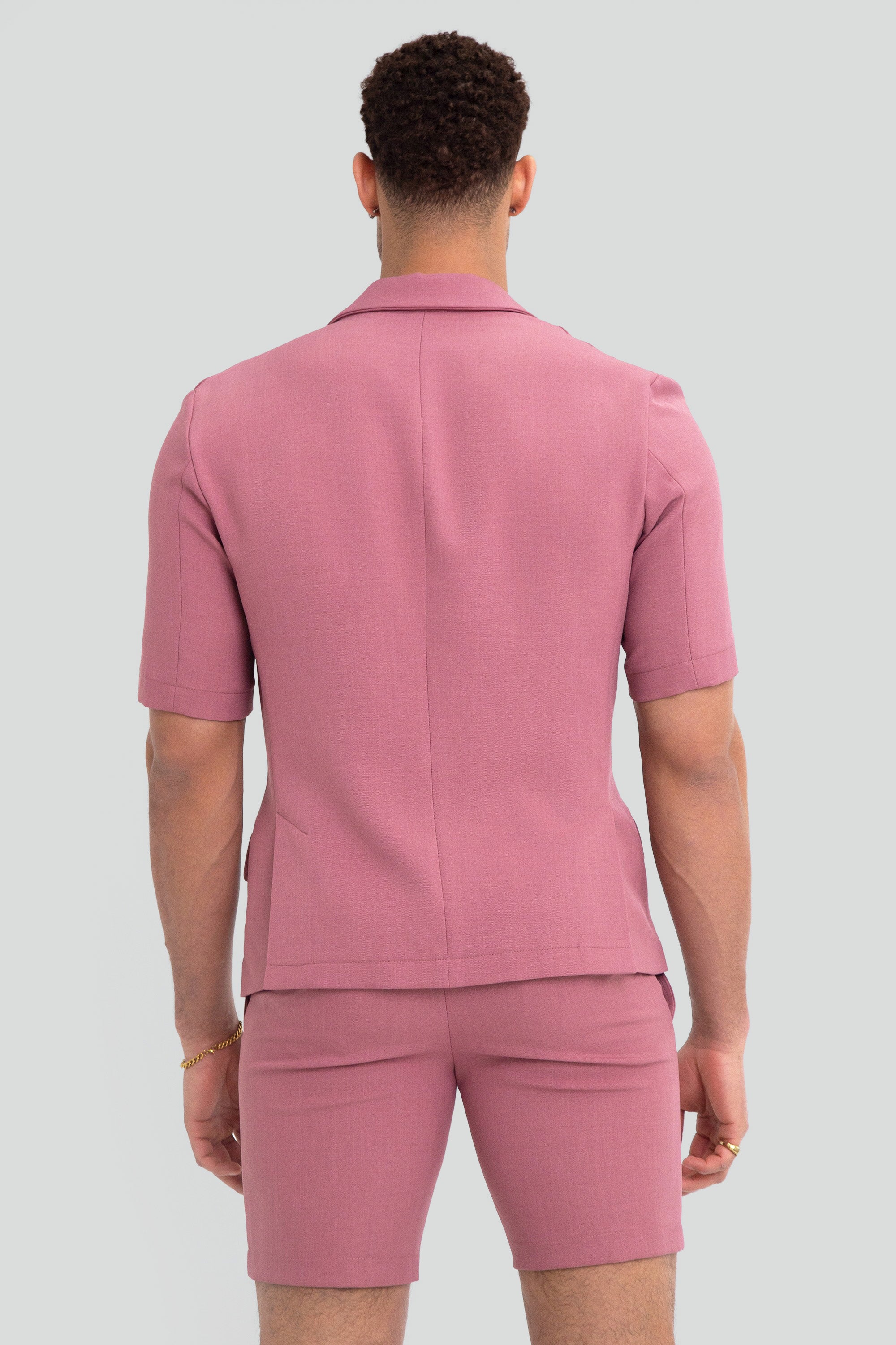 Man wearing a pink short suit on a plain background