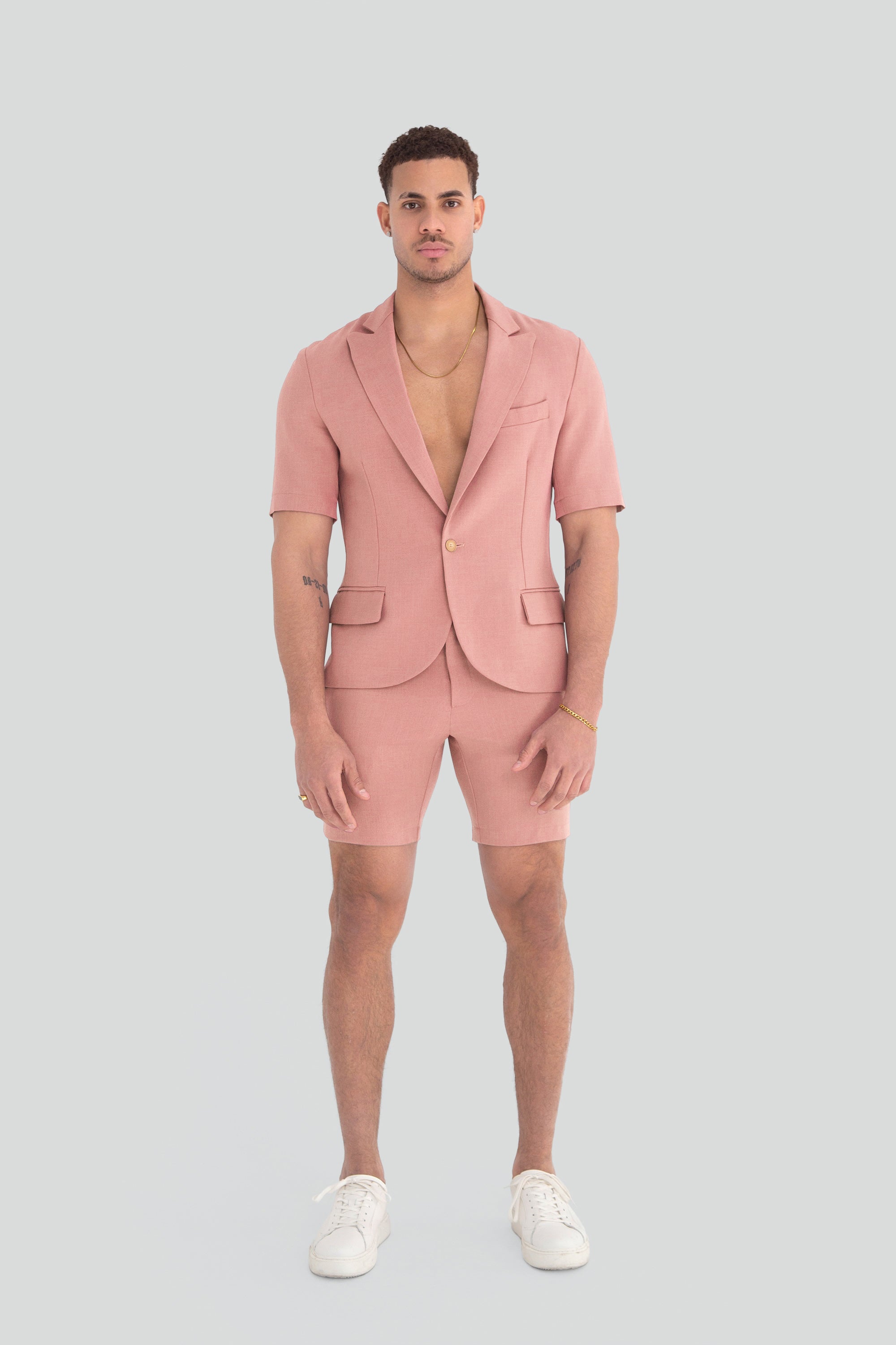 Man wearing a light dusty pink short suit on a plain background