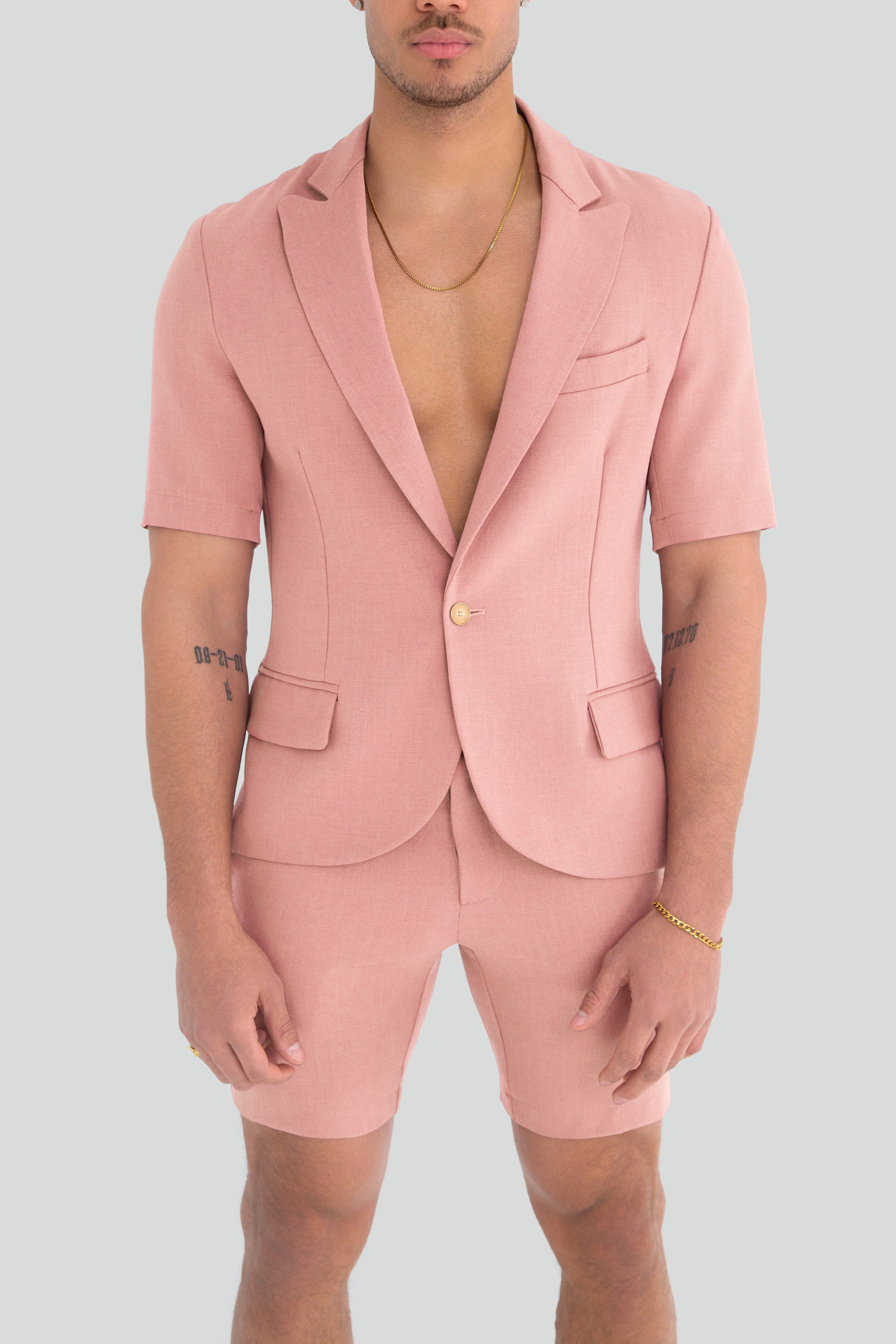 Man wearing a light dusty pink short suit on a plain background