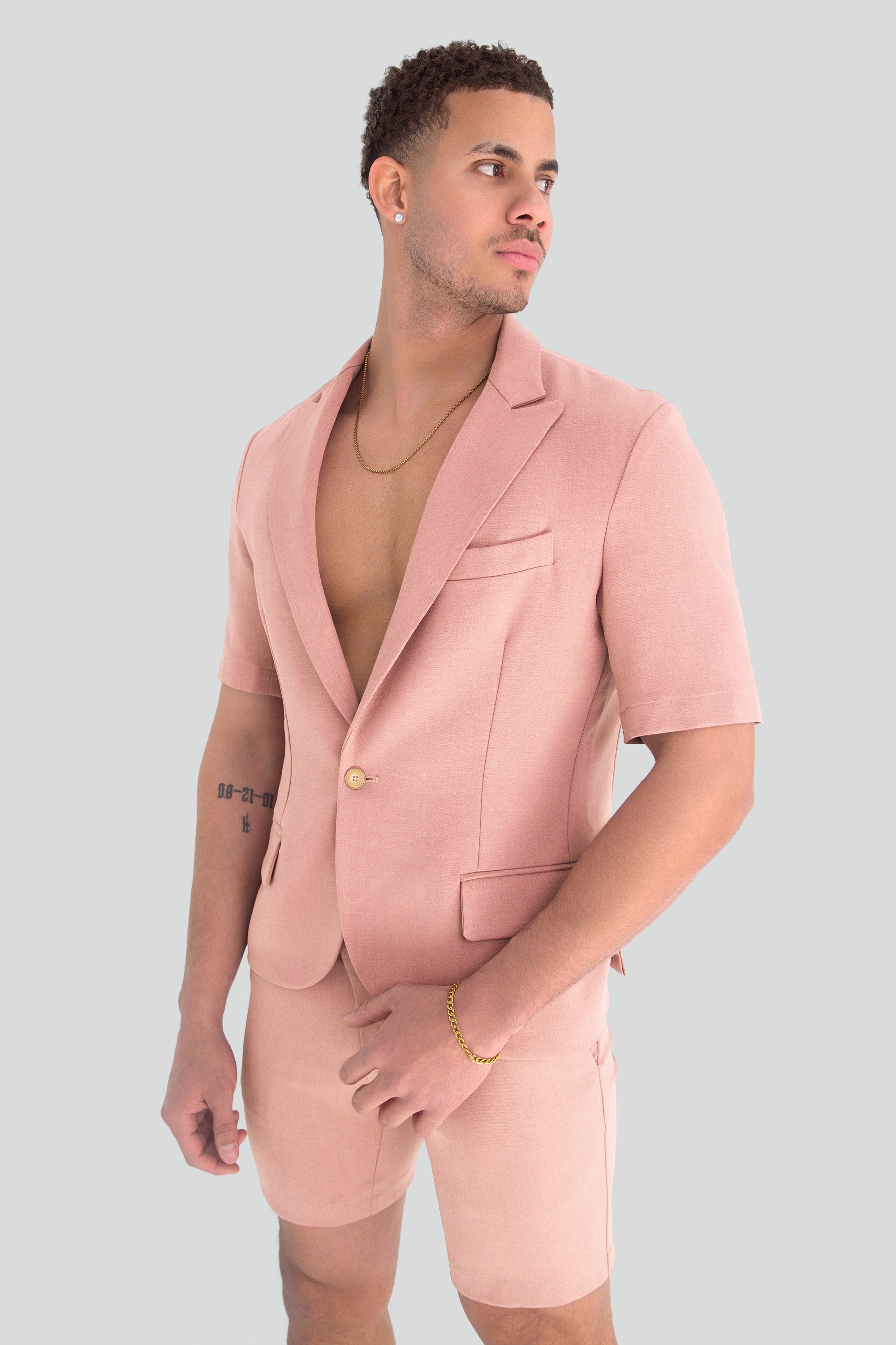 Man wearing a light dusty pink short suit on a plain background